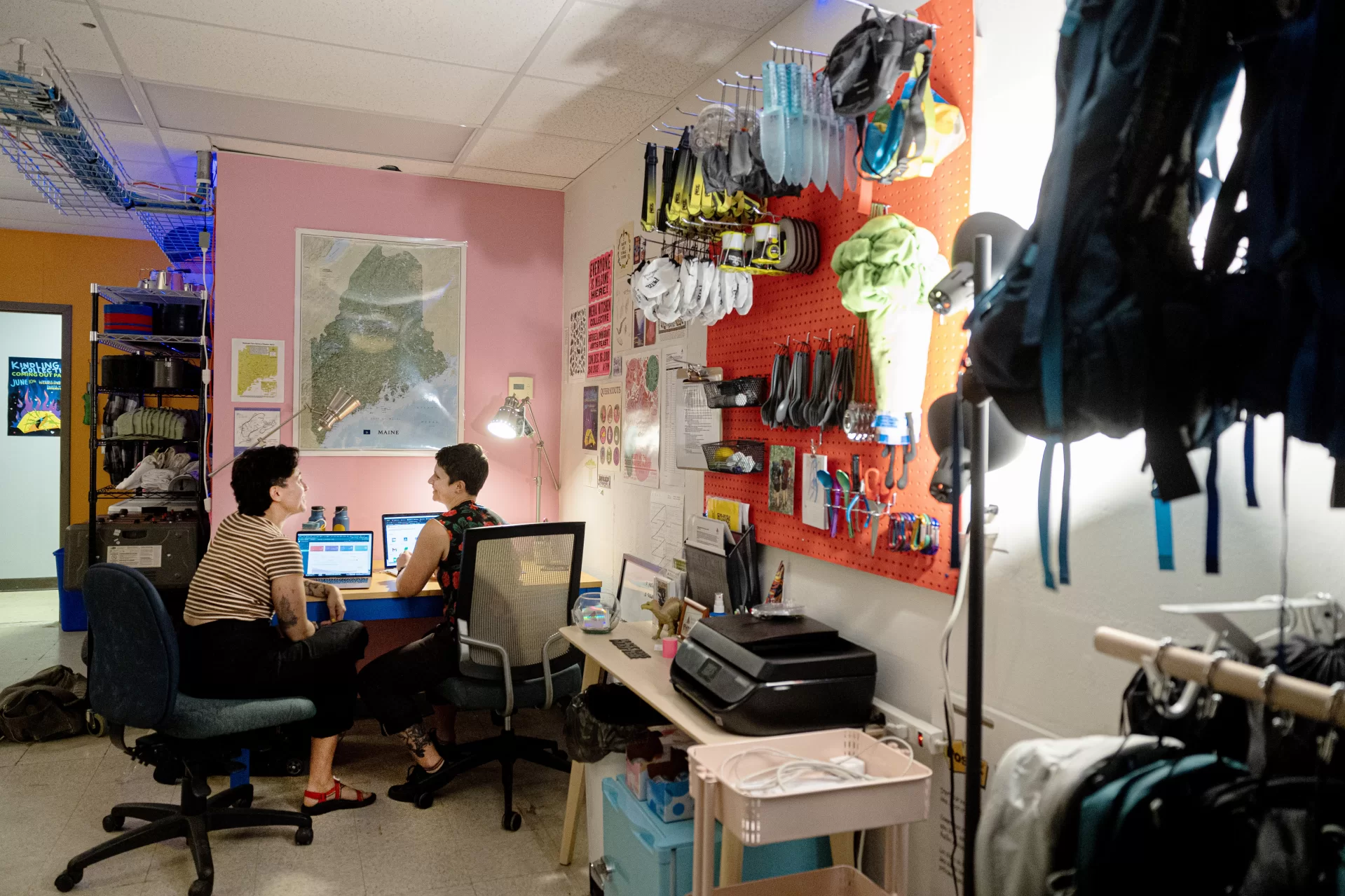 In the basement of Portland’s Equality Community Center, Portland’s newest gear library lacks the store-front appeal of the many outdoor retail shops in a state famous for its outdoor recreation. But one step inside Kindling Collective during its open house on June 10 and the orange and pink walls, the sound of laughter, and the mini outdoor-gear lessons breaking out spoke of a warm, welcoming community and, most of all: joy.

Kindling Collective, a gear library focused on the queer community, was founded this spring by business partners, spouses and outdoor enthusiasts Hallie Herz ‘11 (wearing striped shirt) and Eva Fury in an effort to help the LGBTQ+ community access the outdoors in a safe, fulfilling and affordable way. 

The tiny 400-square-foot space welcome everyone, though it's focused on helping queer people specifically feel welcome, empowered and inspired. Focusing on joy, Hertz said, is central to their mission.

Hertz and Fury were photographed at 15 Casco St. on June 15, 2023.