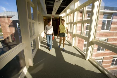 Seniors Amanda Chisholm, at left, and Megan Patey cross a bridge between sections of the new student residence. Much of what's exciting about Bates' new student residence at 280 College St. is captured in one unlikely area: the laundry room.