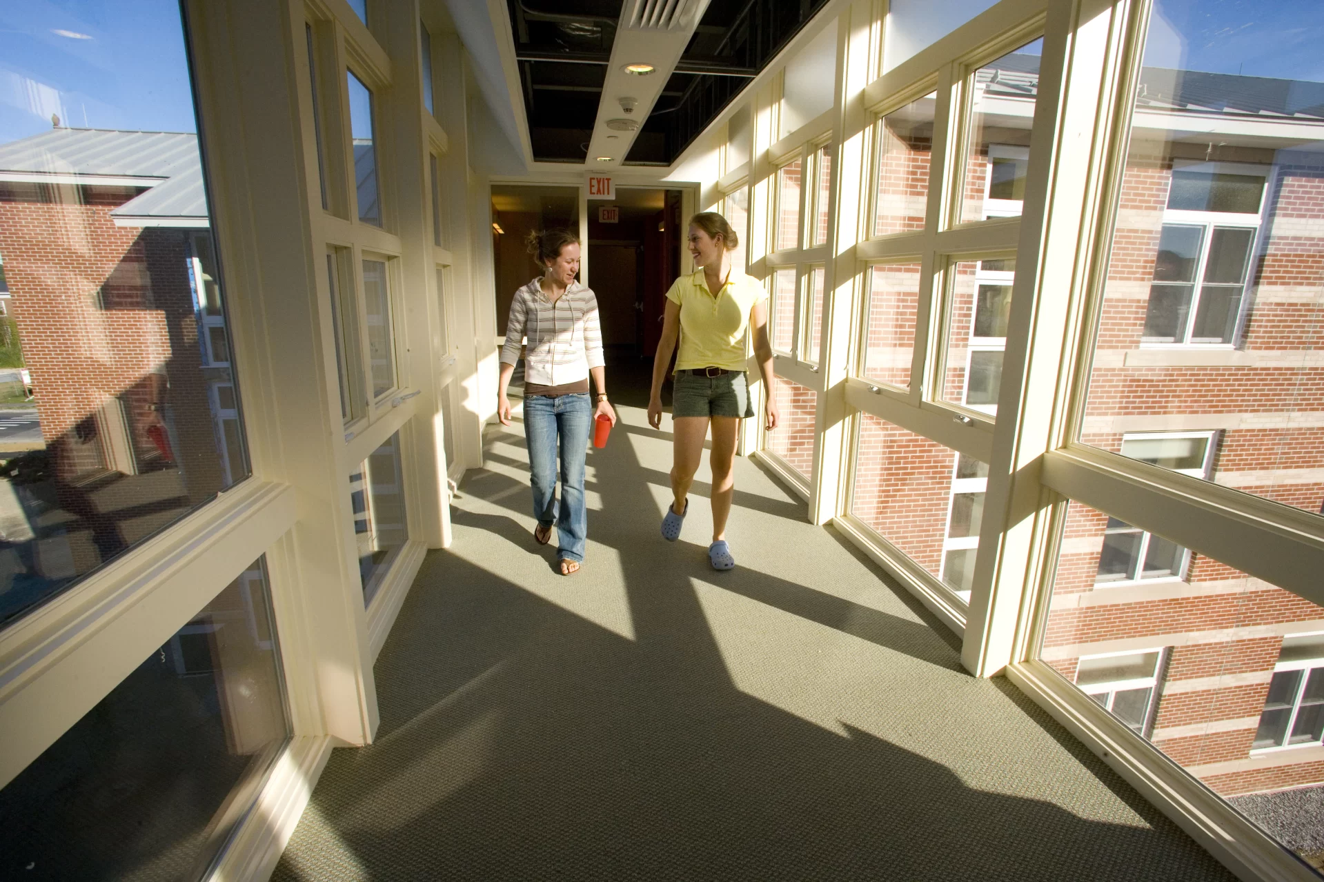 Seniors Amanda Chisholm, at left, and Megan Patey cross a bridge between sections of the new student residence.

Much of what's exciting about Bates' new student residence at 280 College St. is captured in one unlikely area: the laundry room.