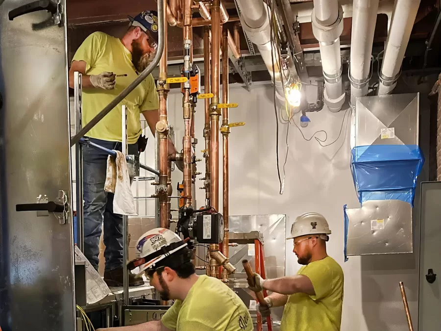 Mechanical engineers connect the new energy recovery ventilation unit in Chase Hall. (Doug Hubley/Bates College)