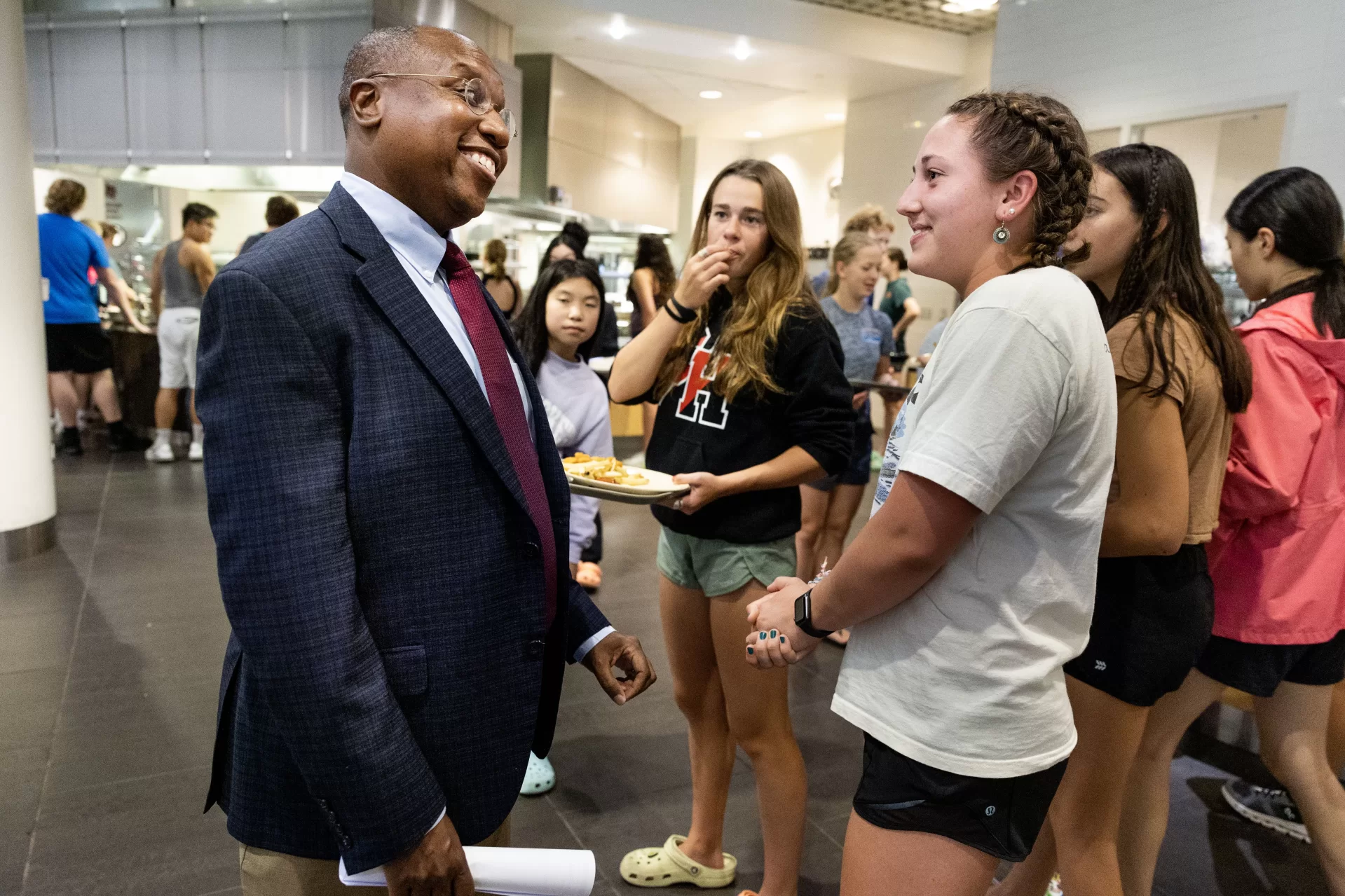 Vice President for Academic Affairs and Dean of the Faculty Malcolm Hill takes President Garry Jenkins to Commons for his first meal, where after choosing his lunch and greeting various diners, he meets with faculty and staff in Commons 221 to discuss HHMI, Mellon, and Sherman Fairchild teams.

Day Five for the ninth Bates president — who officially became president on July 1 — was anything but a 9-to-5 affair, but instead a chance to explore the campus and meet as many folks as possible. After an early-morning walkthrough of Lane Hall, where he has his office, and the beverage break, provided by our Curb Cats food truck team, Jenkins took his first meal in Commons, a working lunch with faculty who are leading a few different academic initiatives.

McKayla Kendall ’26 was navigating the different lunch options at Commons on Wednesday when she saw the man she’s followed on Instagram. The Bates swimmer and Bobcats Swim Club counselor didn’t hesitate to approach the college’s new president. 

“You’re Garry, right?” Kendall boomed, before asking, of all things, about Taylor Swift. 

As Garry W. Jenkins moved through Bates campus during a daylong tour on his fifth day as president, he was more than happy to stop, discuss, and share his knowledge as a “Swifty.”

“This is a very, very cool president. I’m excited,” Kendall said. “I saw on Instagram he went to see Taylor Swift with his husband in Minnesota. Of course I’m going to mention that. We talked about her surprise songs at her concert.”