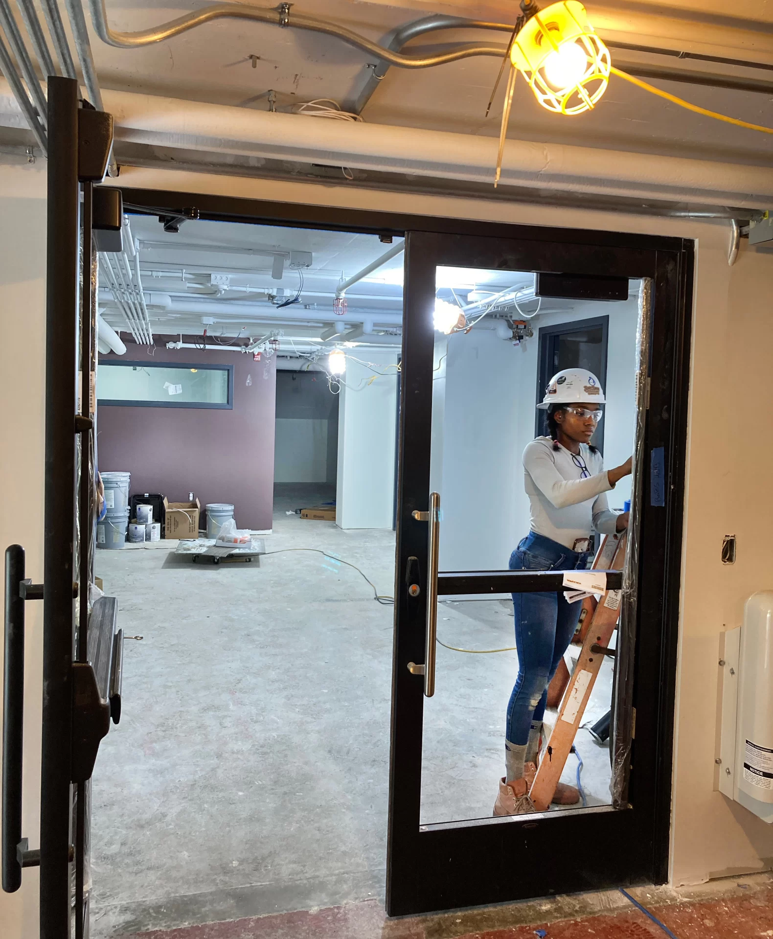 A glazier for Cumberland County Glass touches up a new door at the entrance to the Residence Life office suite. (Doug Hubley/Bates College)