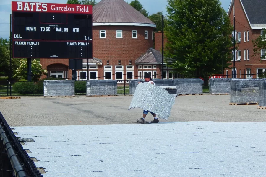 Placing shock-absorbing turf pads on Garcelon Field as an underlayment for the forthcoming Legion playing surface. (Doug Hubley/Bates College)