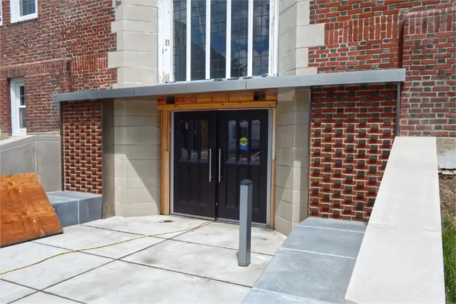 The reconstruction of Chase Hall’s main Campus Avenue entrance was nearly complete on Aug. 1, with just some missing trim and cleaning up to attend to. The doors predate the building’s renovation and were refinished for it. Note the textured brick pattern where the benches meet the building: projecting Flemish bond. (Doug Hubley/Bates College)