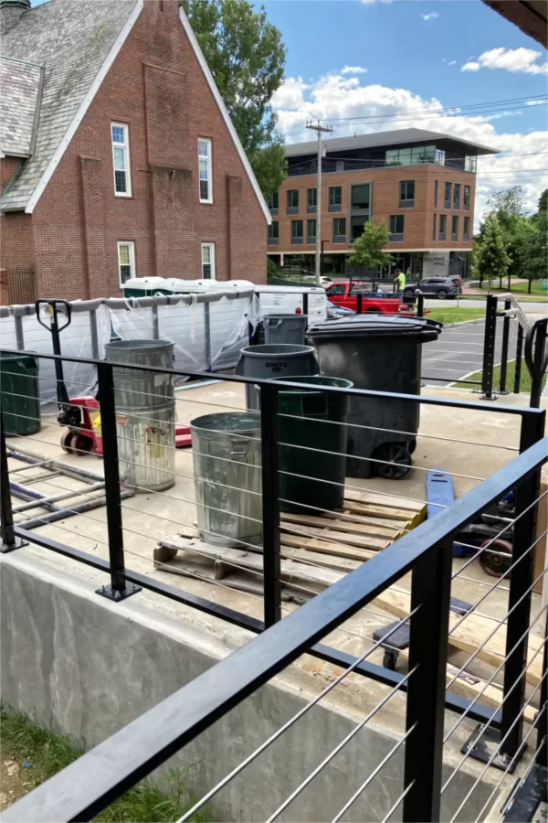 One outcome of the July 25 stormwater backup into Chase Hall was a profusion of trash cans staged on the loading dock for emptying. But soon the dock, with furniture like something from a Parisian sidewalk cafe, will be a place for repose and for socializing. (Doug Hubley/Bates College)