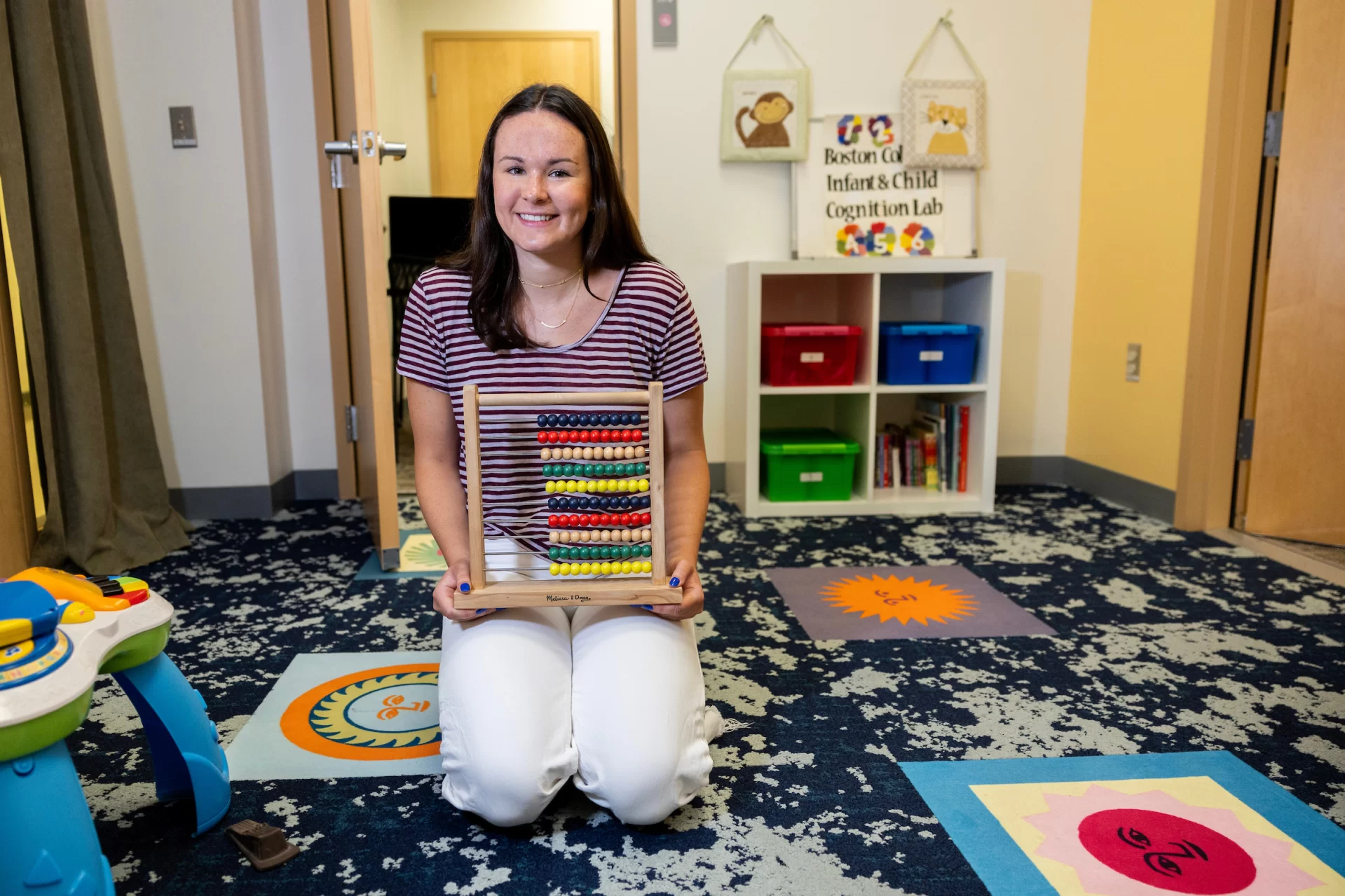 Lydia Barker ’25 of, Wellesley, Mass., a psychology, has a Purposeful-Work funded internship with the Infant and Child Cognition Lab at Boston College under Sara Cordes.

Barker posed for portraits in from of BC’s McGuinn Hall, and inside of the Boston College Infant and Childhood Cognition Lab, where she has spent the summer participating in a study of how children develop their understanding of numbers.

The Infant and Child Cognition Lab is situated in the Psychology and Neuroscience Department at Boston College, headed by Dr. Sara Cordes. Research in the lab focuses on understanding how infants, children, and adults keep track of quantity and how social contexts influence math learning.