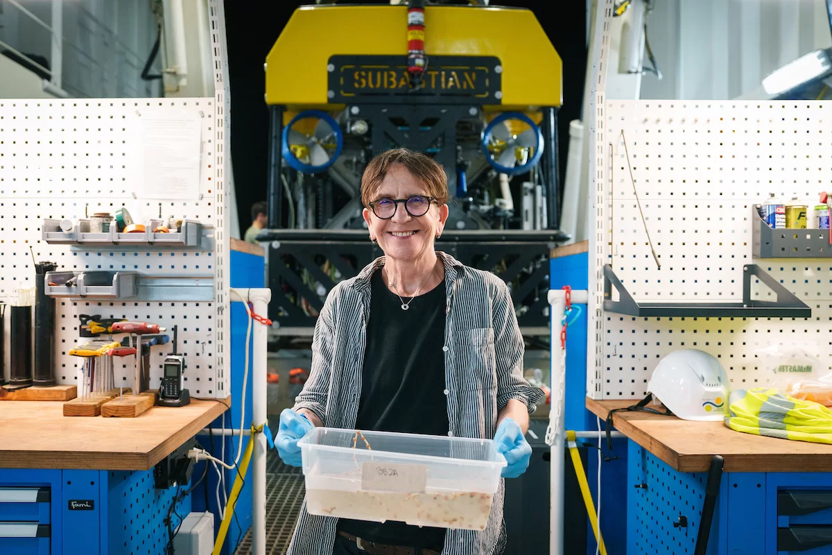 Michel Droge (Artist, Bates College) puts down the bruses and picks up a container to assist the science team with removing samples from ROV SuBastian. (Photo courtesy of the Schmidt Ocean Institute)