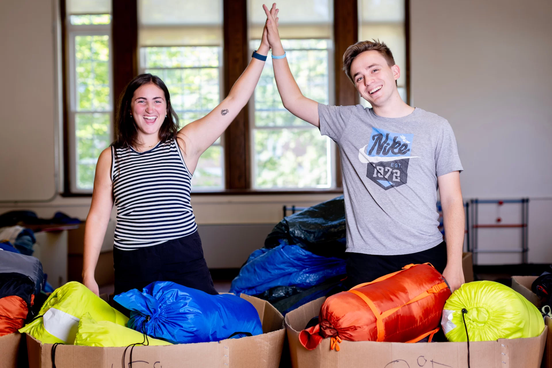 ASEOP coordinators Casey Shultis ’24 of Portland, Ore., and Maeve McSloy ’24 of Old Greenwich, Conn., pose for portraits outside and inside of  Chase Hall, where they are using Memorial Commons as a gathering center for equipment and food for upcoming AESOP trips for the incoming Class of 2027.