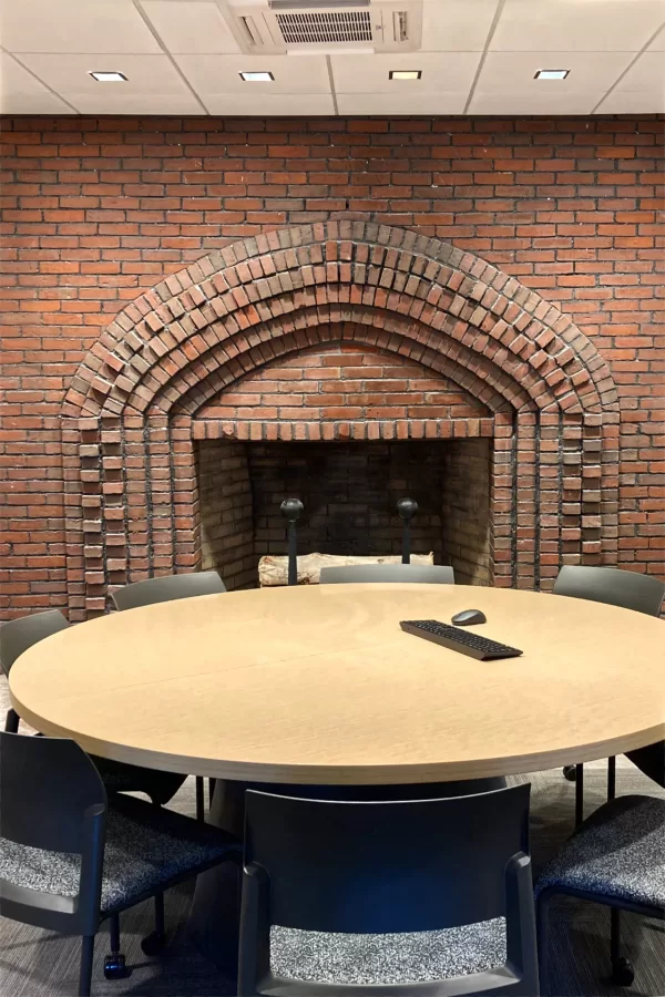 This meeting room in Chase Hall’s new Student Affairs office suite houses a rugged fireplace original to the century-old building. The projecting brick pattern is replicated in decorative brick insets flanking the main Chase entrance. (Doug Hubley/Bates College)