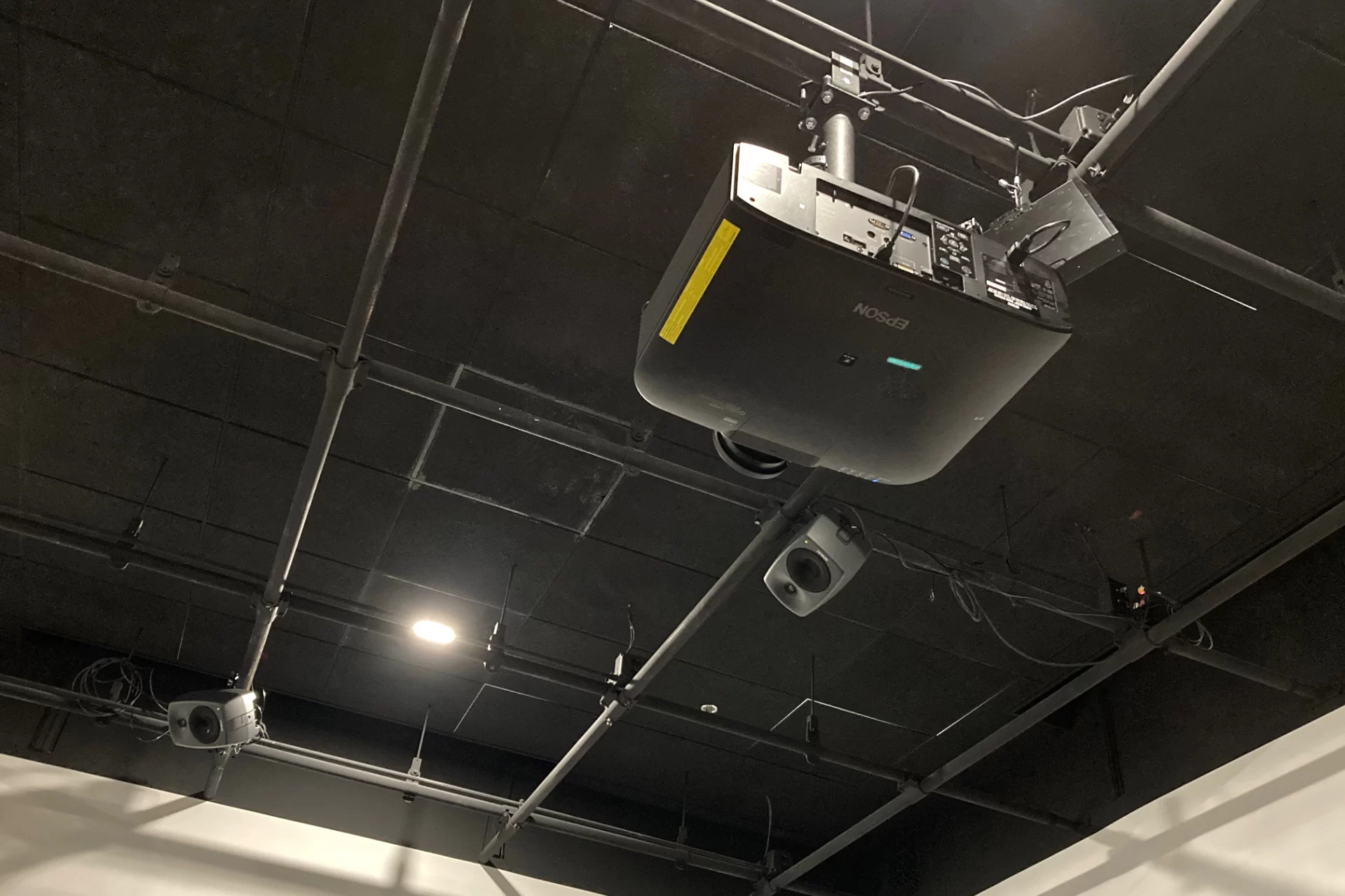 An image projector and speakers mounted on the ceiling grid of the Immersive Arts Studio. (Doug Hubley/Bates College)