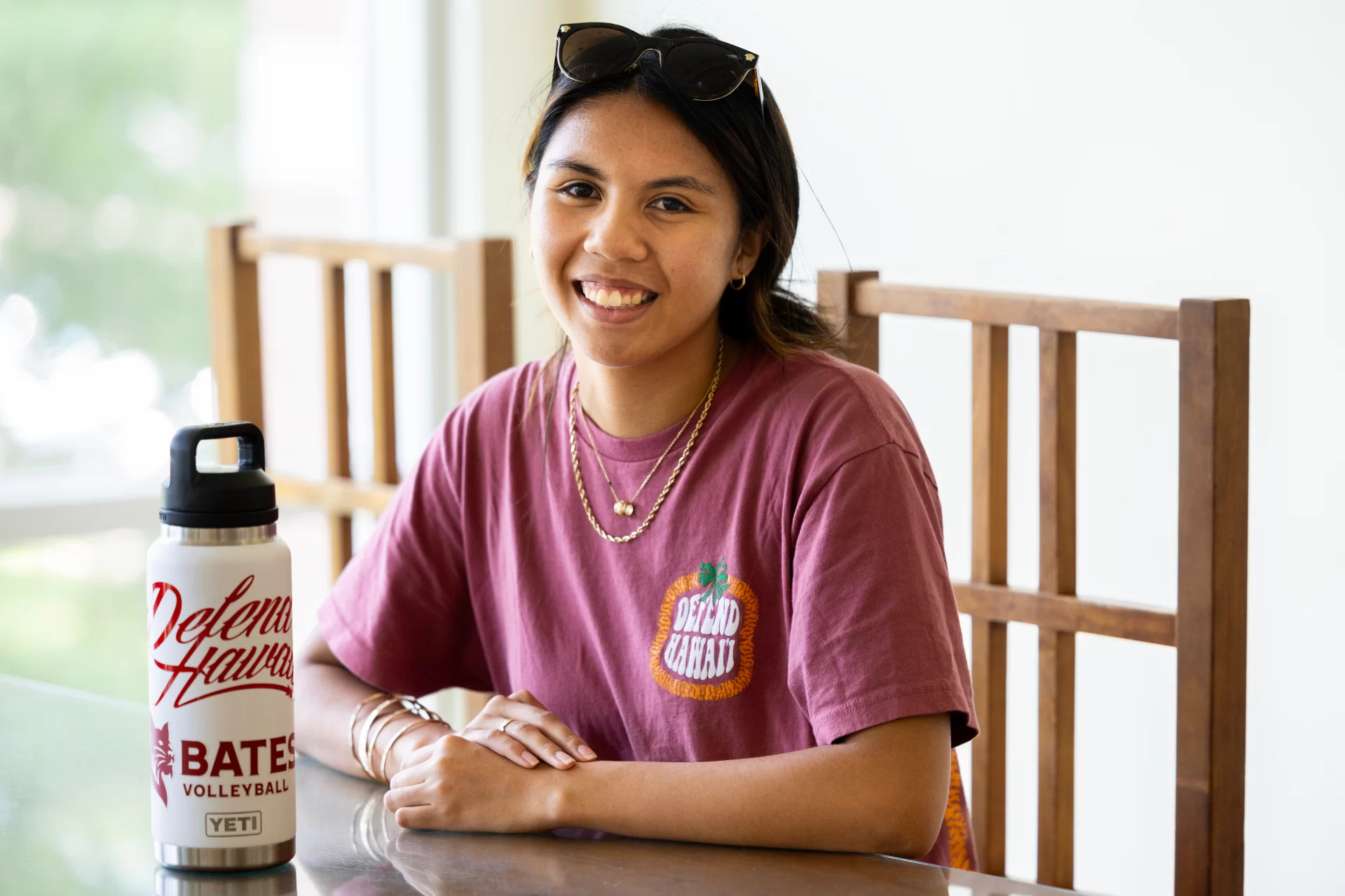 Kaneohe, Hawaii, poses with a t-shirt and Water bottle in connection with a fundraiser that her Bates volleyball team running to support Maui residents who lost family members and property  in the Lahaina wildfires.