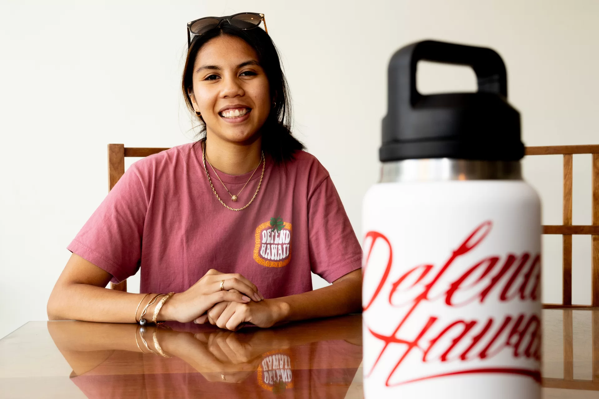 Kaneohe, Hawaii, poses with a t-shirt and Water bottle in connection with a fundraiser that her Bates volleyball team running to support Maui residents who lost family members and property in the Lahaina wildfires.
