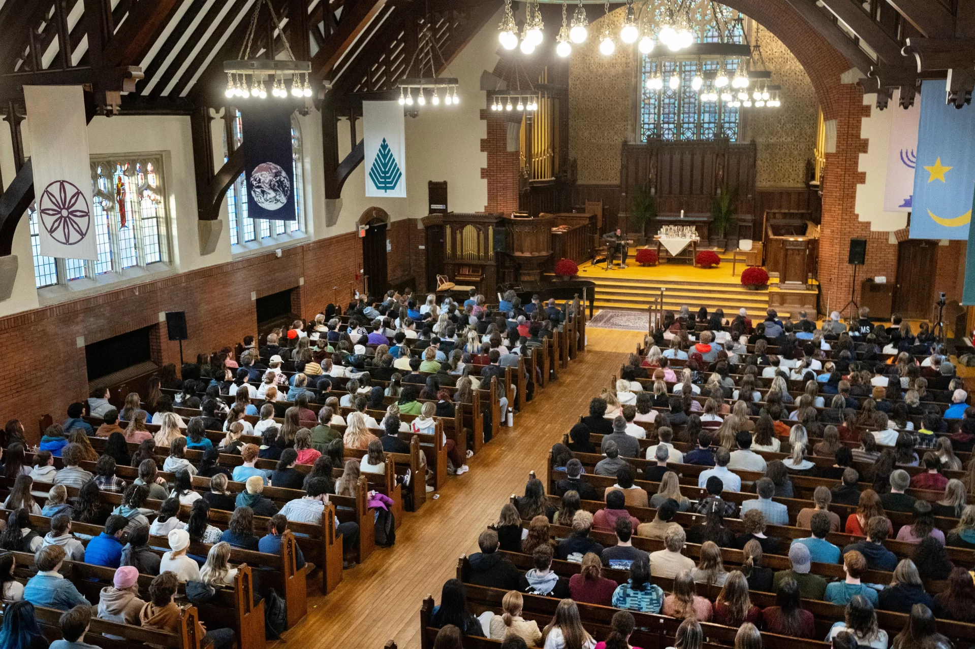 “The brightness that shines through the dark of a tragedy such as we have suffered here in Lewiston, our home, is what it always is in times like these: the immense capacity of our shared humanity,” said Bates President Garry W. Jenkins in his remarks during today’s Vigil for Grief and Remembrance, held at 4:30 p.m. in Gomes Chapel on the one-week anniversary of the shootings in Lewiston.
Led by the Rev. Brittany Longsdorf, the college’s multifaith chaplain, the vigil gave the campus community an opportunity to come together for silence, candle lighting, poetry, and interfaith prayers, and, ultimately, to share communal grief with their Lewiston community.
Welcome & Naming Grief: Brittany Longsdorf,
Multifaith Chaplain and Visiting Lecturer in the Humanities
Bates President Garry W. Jenkins Remarks
Lewiston Mayor Carl Sheline’s Remarks
Invitation for Sharing: Brittany Longsdorf
*Barry Music* (single floor mic, guitar output)
Reading of the Names: Brittany Longsdorf and Raymond Clothier, associate multifaith chaplain
• Tricia C. Asselin
• Peyton Brewer-Ross
• William Frank Brackett
• Thomas Ryan Conrad
• Michael R. Deslauriers II
• Maxx A. Hathaway
• Bryan M. MacFarlane
• Keith D. Macneir
• Ronald G. Morin
• Joshua A. Seal
• Arthur Fred Strout
• Stephen M. Vozzella
• Lucille M. Violette
• Robert E. Violette
• Joseph Lawrence Walker
• Jason Adam Walker
• William A. Young
• Aaron Young
*moment of silence* & closing, begin to pass candle lighting
READINGS (all from Lectern mic unless noted)
Aneeza Ahmad ‘25 of Sharon, Mass., and Alaina Rauf ‘25 of Yarmouth, Me., of the Bates Muslim Student Association
Sophie Leight ‘26 of Easton, Md.
Venerable Tenzin Dasel, ‘88 - volunteer spiritual advisor and founder of the Maine Mindfulness Project and is an active retreat leader and speaker in the International Network of Engaged Buddhists
Levi Mindlin ‘24 of Portland, Ore - song (single floor mic, guitar output)