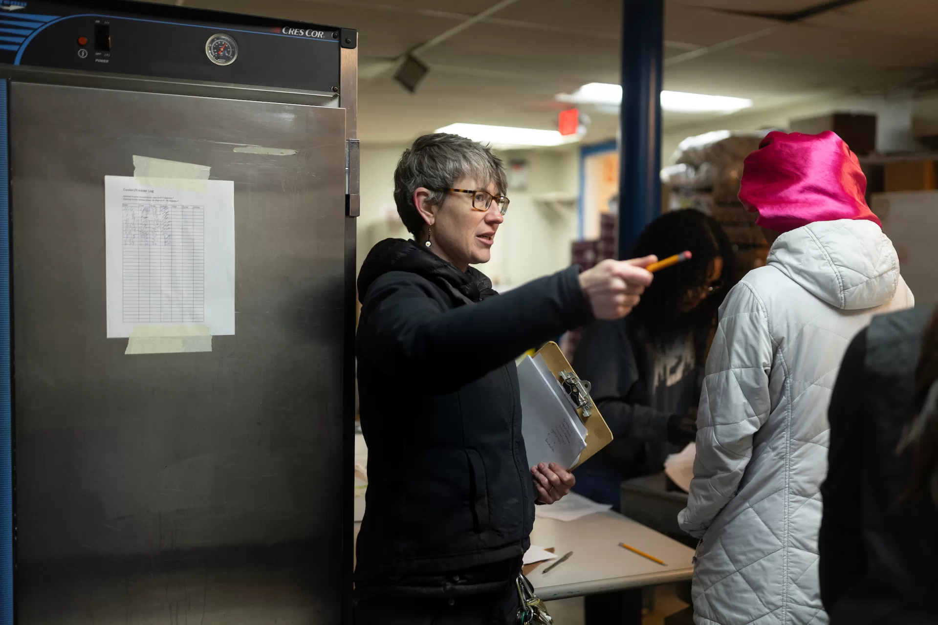 Erin Reed ’08, executive director of the Trinity Jubilee Center in Lewiston, works in the organization’s food bank on Nov. 30, 2023, after which she relocates into the center’s shelter while on her computer. Shown with her mentor and retired ED Kim Wetlauffer ’80.