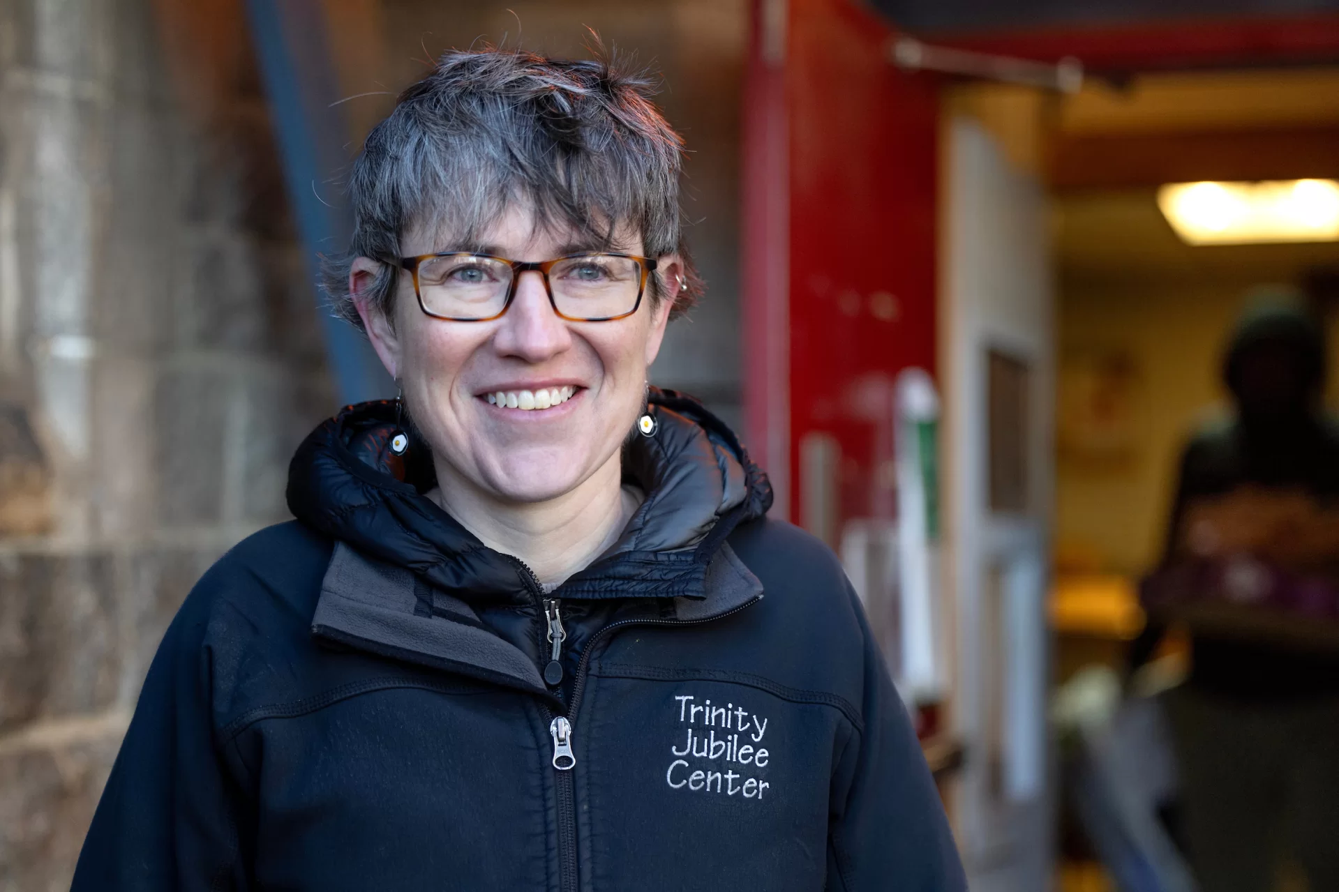 Erin Reed ’08, executive director of the Trinity Jubilee Center in Lewiston, works in the organization’s food bank on Nov. 30, 2023, after which she relocates into the center’s shelter while on her computer. Shown with her mentor and retired ED Kim Wetlauffer ’80.