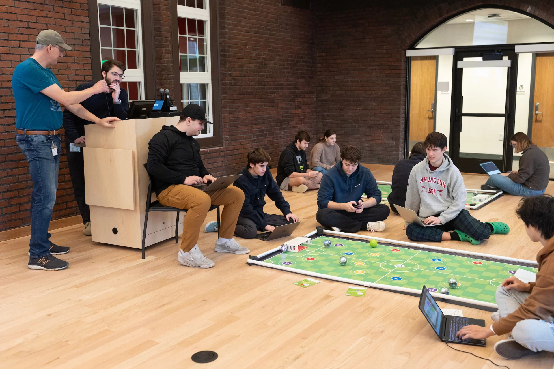 Small, but sophisticated.

That’s what first-year students of Professor of Mathematics Meredith Greer discovered about one kind of small robot during a visit to Bates by a team of Lewiston Public Schools educators on Nov. 14.

The team of instructional specialists and tech coaches brought Sphero BOLT robots with them during the morning visit to Chase Hall Lounge. Designed for educational and recreational purposes, they’re often used in schools to teach coding and robotics.

From left, first-year students Darien Chiang of Quincy, Mass., Julian Tilney of Arlington, Mass., and Finn Sheehy of Burlingame, Calif., get a handle on how to program the robots.

The students are in Greer’s First-Year Seminar, “Learning Math Using Crafts, Coding, and Games,” which investigates “how humans think about math at age 5, age 12, or age 18 and beyond.” During the semester, the students focused on learning through a variety of methods, including hands-on crafts, open-ended class meetings, and age-appropriate computer coding.

This was the educators’ third visit to the course, and for each visit, they brought with them age-appropriate robots.

Connecting with the Lewiston educators, and gaining insights into “specific activities they do with the robots at specific grade levels,” Greer explains, “has given us multiple chances to connect our studies with specific grade-level-based math learning standards that are used across the state of Maine.”

For the Lewiston educators, the three visits reflect growing outreach efforts into their community. “They were both enthusiastic and generous about bringing these lessons into our classroom,” says Greer. “Moving forward, we are continuing to think about ongoing collaborations.”