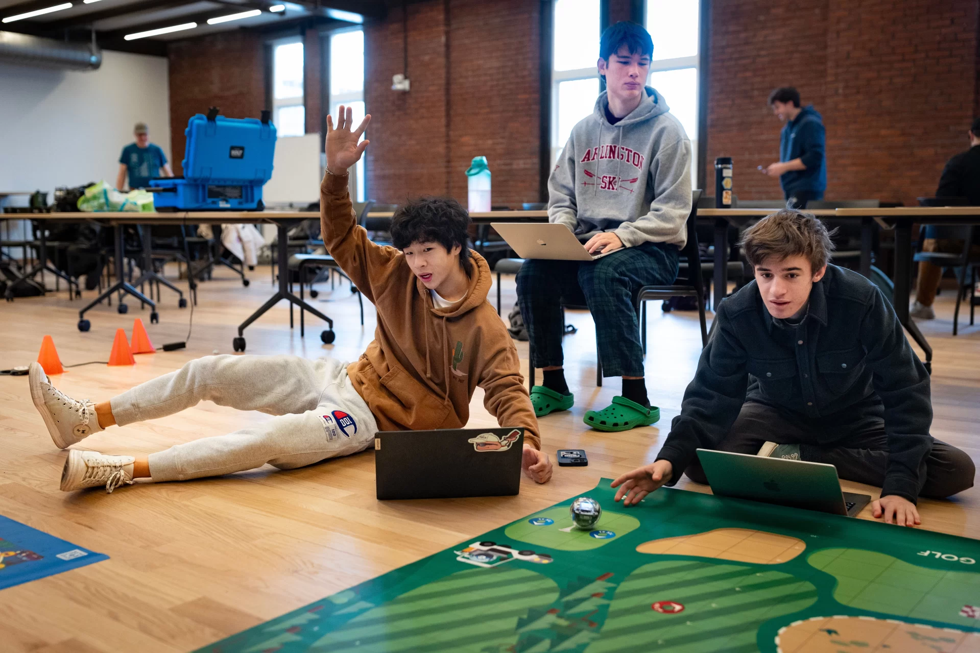 Small, but sophisticated.

That’s what first-year students of Professor of Mathematics Meredith Greer discovered about one kind of small robot during a visit to Bates by a team of Lewiston Public Schools educators on Nov. 14.

The team of instructional specialists and tech coaches brought Sphero BOLT robots with them during the morning visit to Chase Hall Lounge. Designed for educational and recreational purposes, they’re often used in schools to teach coding and robotics.

From left, first-year students Darien Chiang of Quincy, Mass., Julian Tilney of Arlington, Mass., and Finn Sheehy of Burlingame, Calif., get a handle on how to program the robots.

The students are in Greer’s First-Year Seminar, “Learning Math Using Crafts, Coding, and Games,” which investigates “how humans think about math at age 5, age 12, or age 18 and beyond.” During the semester, the students focused on learning through a variety of methods, including hands-on crafts, open-ended class meetings, and age-appropriate computer coding.

This was the educators’ third visit to the course, and for each visit, they brought with them age-appropriate robots.

Connecting with the Lewiston educators, and gaining insights into “specific activities they do with the robots at specific grade levels,” Greer explains, “has given us multiple chances to connect our studies with specific grade-level-based math learning standards that are used across the state of Maine.”

For the Lewiston educators, the three visits reflect growing outreach efforts into their community. “They were both enthusiastic and generous about bringing these lessons into our classroom,” says Greer. “Moving forward, we are continuing to think about ongoing collaborations.”