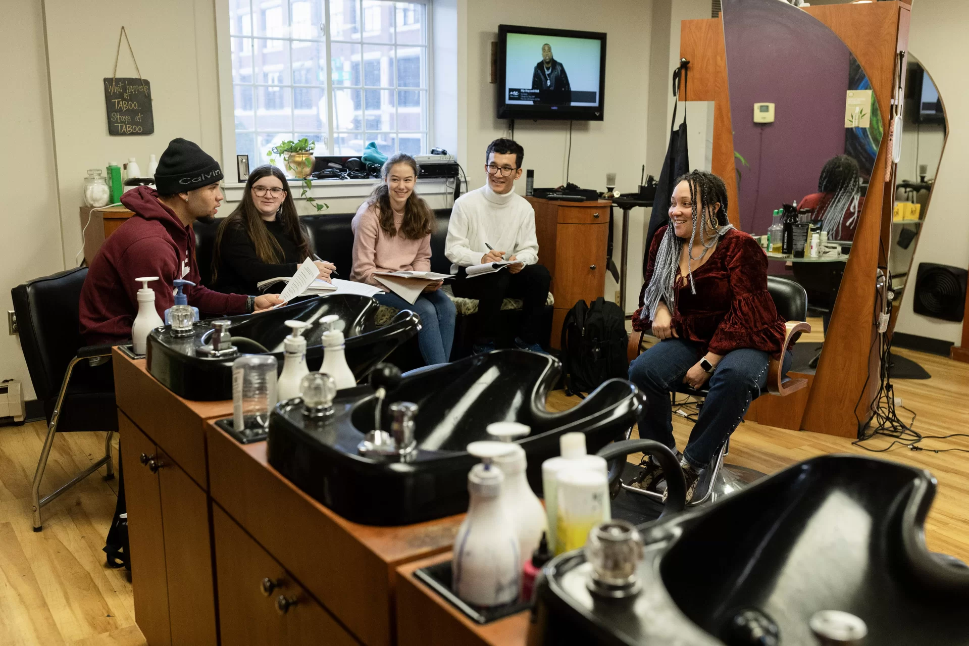 Carly Bauer ’27 (black top), Isabelle Bensen ’27 of Norwich, Vt. (white sweater), Nur Rajaie ’27 of Chicago (white sweater and glasses), and Michael Spencer ’27 (black hat) of Mansfield, Texas, visit stylist Rosa Storer at Taboo Hair Design, 28 Bates St, Lewiston, on Nov. 28, 2023, to interview her as a Community Educator for their class Africana 100, co-taught by Charles Nero and Josh Rubin. The focus of the interview was on a section of the course on “Blackness and Beauty.”