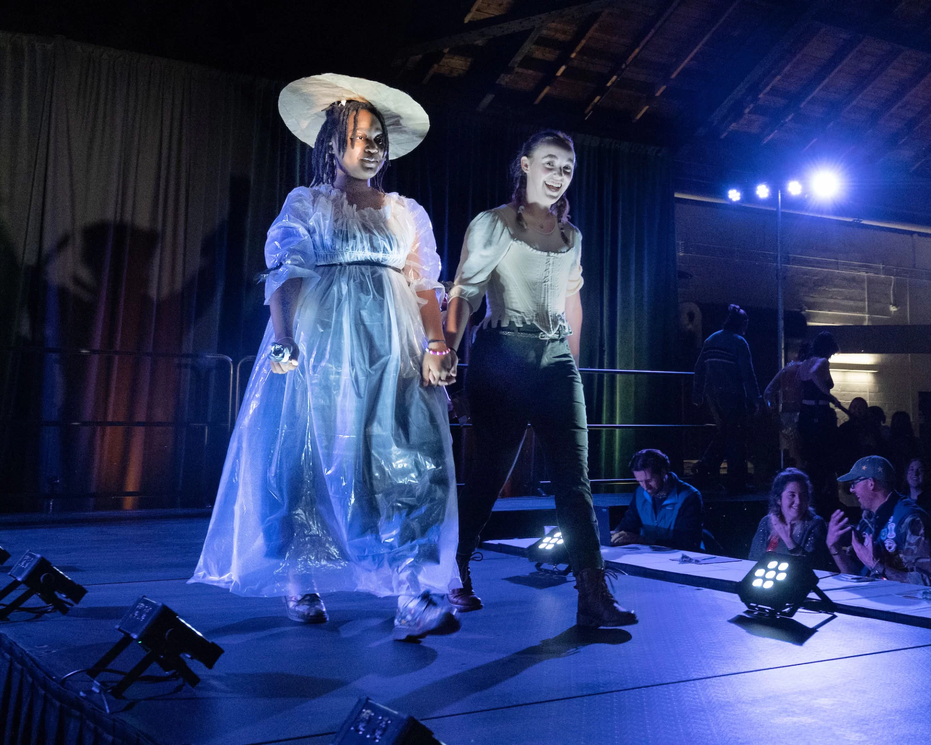 The Trashion Show, including Harvest Meal desserts served by Bates College Dining  in Commons on Nov. 16, 2022, was held in the Christian Daggett Gray Athletic Building.

Contestants:
First Place: Miguel Pacheco '24, wearing stilts and a dress made of recycled book covers, created by Sloan Phillips '25.
Second Place: Bora Lugunda '25, wearing a Marie Antionette-inspired gown made from trash bags and plastic sheeting, and a hat made from cardboard and brown packing paper, created by Grace Acton '24
Third place: Claire Barlass '25, wearing a self-designed "milk dress" made from discarded milk cartons from Commons, an outfit that was also her Halloween costume this year.

Quinn Macauley '24, wearing a "mermaid-inspired" outfit made from trash/discarded swim gear from Tarbell Pool, created by Talia Skaistis '25 and Lianna Rosman '26, all three students are on the Bates Swimming and Diving TeamLily Ritch '25, wearing a "puffy jacket-inspired" outfit made from discarded bubble wrap, chip bags, coupons, mesh orange bag, and straws, created by Emma Righter '23, and accessories by Ella Lungstrum '23 .Leen Dockery '26, wearing a self-created cowgirl-inspired outfit made from discarded cardboard from the Parker 4th floor recycling bin. (I didn't recognize her in the outfit! I remember her from the Visio Divina photos) (edited) 
3:39
Let me know if you want the self-written descriptions for their outfits. I have the script Theo shared, and I can pick them out (there were a lot of withdrawals, I guess! There are like 13 names on the script)

Plus one more male contestant:
7. As Abraham Lincoln once said: there is nothing like a sour patch kid to brighten your day! In this issue of munchies, Henry Welch, Ben Huston, and Jonah Yaffee design a chic, yet delicious outfit of sour patches, chips, goldfish bags, and other assorted snacks to express the intrinsic human primal desire for food, and boy does it look good.