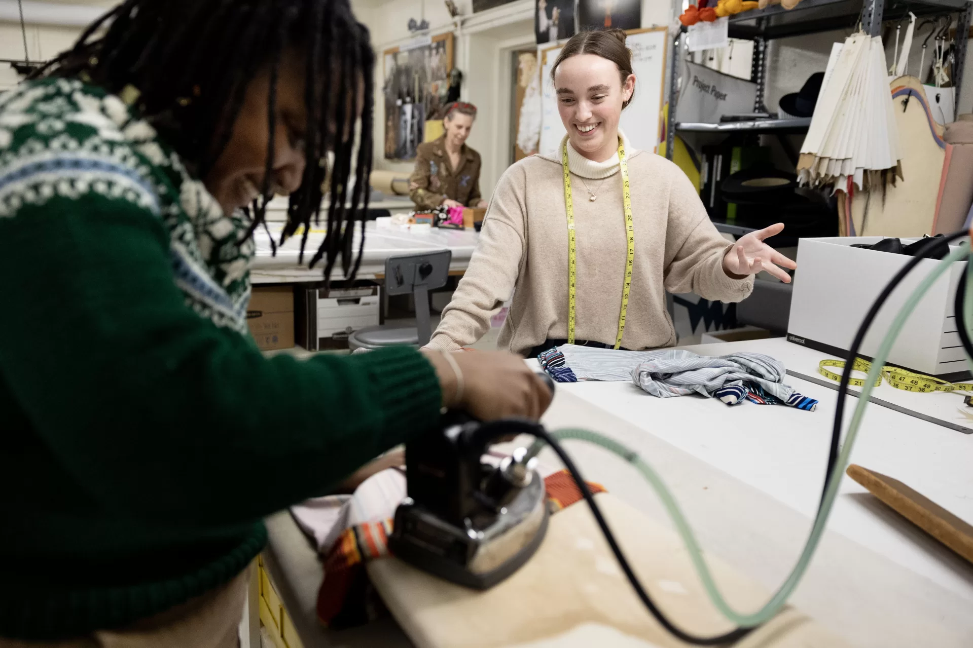 Grace Acton ’24 (in tan sweater) of Harvard, Mass., in costume shop with Carol Farrell, costume shop director, and Bora Luganda ’25 of Kinshasa, Congo, working on costumes for a dance dress rehearsal and enjoying a spot of tea and cake prepared by Farrell. Joined by Adelle Welch ’25 of Livingston, Mont., for tea.