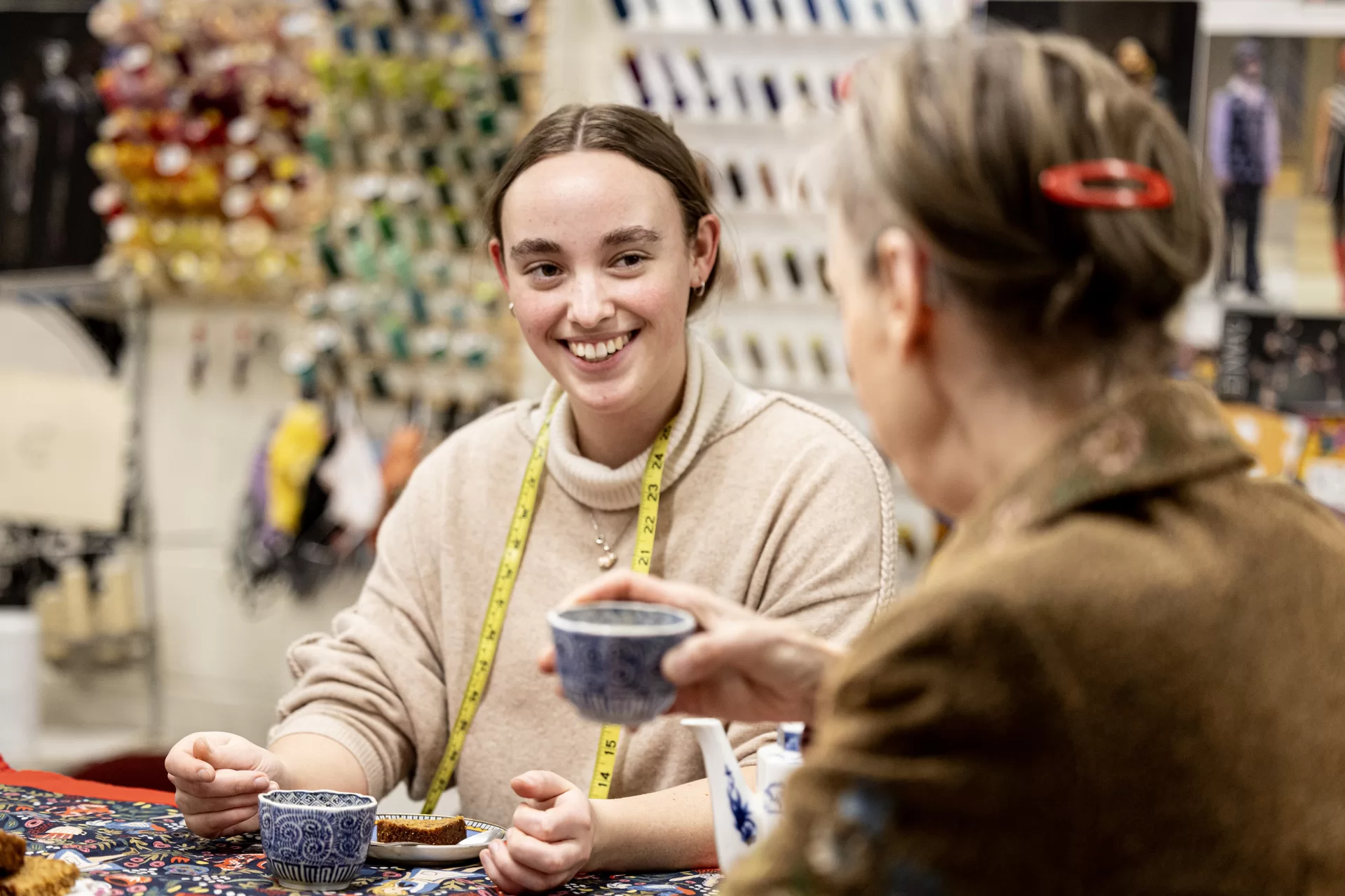 Grace Acton ’24 (in tan sweater) of Harvard, Mass., in costume shop with Carol Farrell, costume shop director, and Bora Luganda ’25 of Kinshasa, Congo, working on costumes for a dance dress rehearsal and enjoying a spot of tea and cake prepared by Farrell. Joined by Adelle Welch ’25 of Livingston, Mont., for tea.