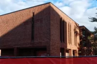 A three-quarter view of 96 Campus Ave. from the street. Concealed behind the construction site fence is the former main entrance. We were interested to see that in a first for a construction project at Bates, management firm Consigli Construction eschewed the forest green that was its longtime choice for fence fabric in favor of a bright red similar to its corporate color. (Doug Hubley/Bates College)