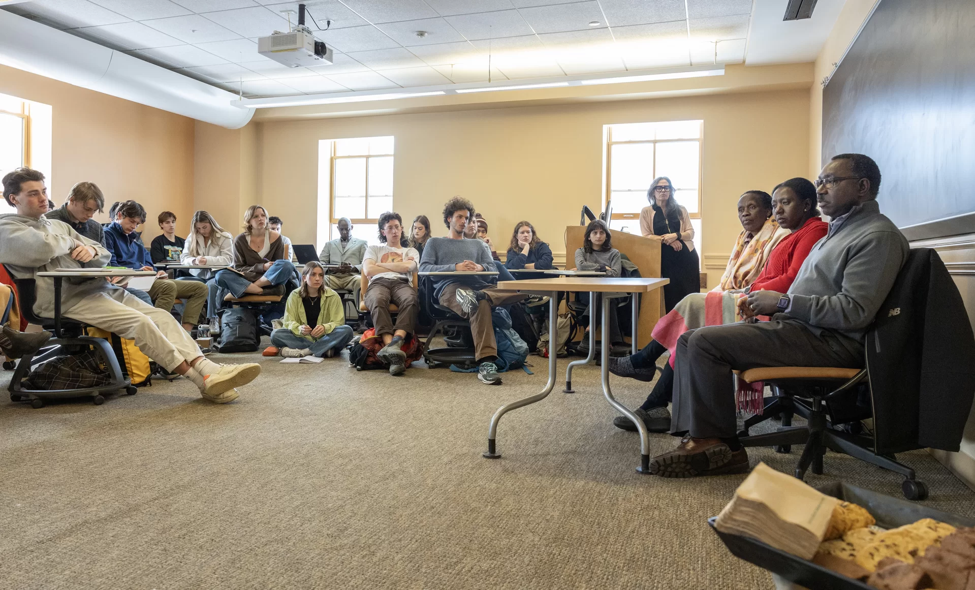 Sitting in the front of a Roger Williams classroom, Rwandan guest speakers Esther Mujawayo (left), Chantal Kayitesi (center), and Jean Bosco Rutagengwa (right) answer questions about their experiences as survivors of the 1994 genocide against the Tutsi of Rwanda in a joint session with three classes on March 25. The Rwandan guests also spoke on March 24 at the Olin Arts Center as part of the three-day event “Rwanda 30 Years After: Trauma Healing of Genocide Survivors and Intergenerational Trauma.” (Phyllis Graber Jensen/Bates College)