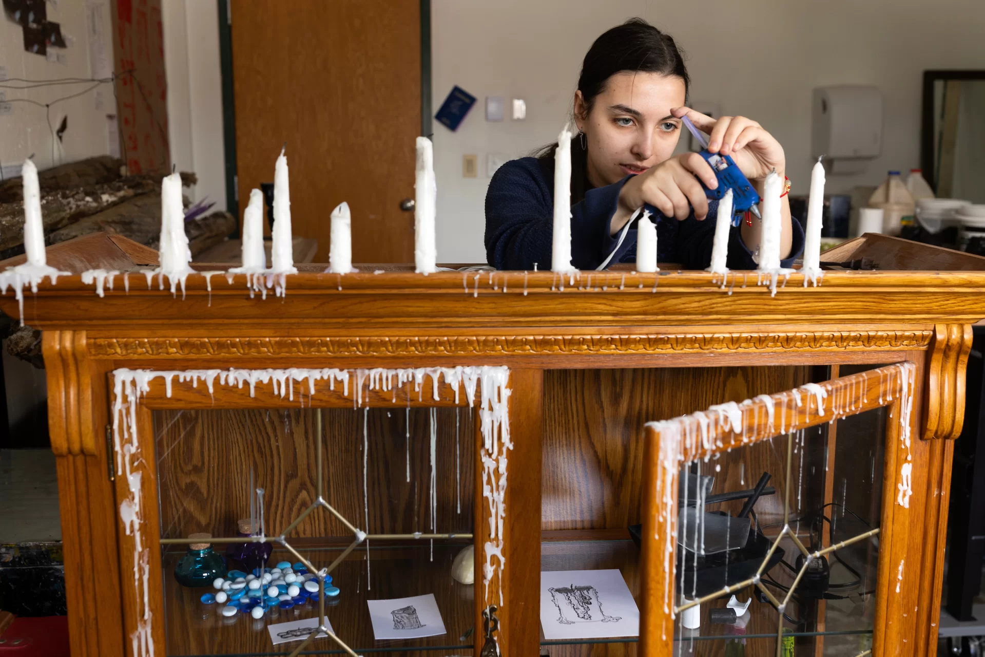 Olivia Rabin ’24 of Montclair, N.J., works in her Olin Arts Center studio on March 21, 2024.

From a young age, I was fascinated by nature and the fantastical. This and the works by people similarly inspired by the natural world inspire my current work. While I am interested in many different things, I am always working to visualize them to help me understand how I connect them internally. In my work, I am trying to synthesize my own process into something tangible and observable. I am exploring the connections between my headspace, the act of expression, and the physical world.

I want to explore the emotions and sensations of the world around me, being captivated by nature and the fantastical. I love the mysterious blues and otherworldly qualities of water, especially found in oceans and waterfalls. I am thoroughly enchanted by them. This was only heightened by my favorite creative works like The Blue Planet by David Attenborough. This film not only allowed me to see the ocean’s depths in ways I had never seen before but also showed me ways in which form can create fantastical emotions out of the real. Works like Hayao Miyazaki’s Laputa: Castle in the Sky expand on this in artistic and sensory ways that become their own mythology. Works by artists like Heikala and Gabriel Picolo expand upon mundane elements of reality, abstracting them into the fantastical. Heikala’s illustrations often explore the magic in mundane moments by abstracting an element like size, time, or location to convey an emotion fantastically. In Picolo’s Icarus and the Sun, the already metaphorical wax of Icarus’ wings becomes more emotional as Icarus’s body is made of wax and the sun becomes his lover. Wax is quite captivating for me as its qualities are intrinsically related to water. Wax flows like water but as it cools and solidifies it almost freezes a moment in time and space allowing for the magic to be captured. In these works, I was able to find connections between my int