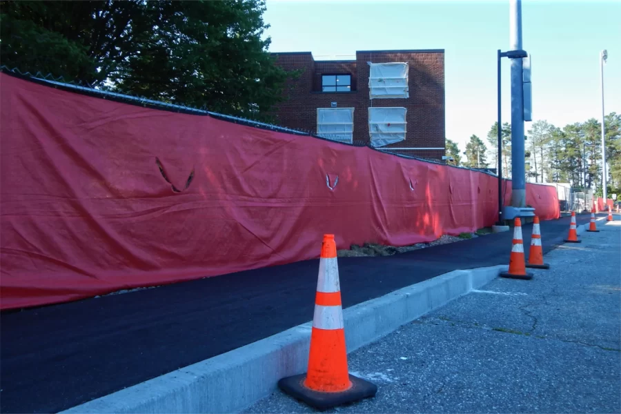 96 Campus Avenue, whose conversion into a Bates student residence will be effectively complete in less than two months, looms above the construction site fence and a new sidewalk along the Facility Services access road. Note the new window unit — one of many to be installed – just above center. (Doug Hubley/Bates College)