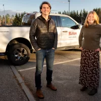When the Bates student EcoReps encounter a sustainability problem that needs solving, they don’t just sit around and debate solutions — they envision and then execute them. In two of their most recent successes, the students helped to secure funding to solve an unexpected problem with the existing electric vehicle chargers on campus and helped purchase a slew of new EVs for campus use. “It's really cool that as students, I feel like we have a voice,” says Martin Carriere ’25, an EcoRep from Davis, Calif. “I always feel like our ideas are heard. We're positioned to have bolder ideas and be able to bring those to the table.” Bates is known for its impressive achievements in sustainability, but the existential threat of climate change gives expanding the work great urgency. Carriere, a double major in politics and environmental studies, and fellow EcoRep Cassidy Meyer ’25, an environmental studies major from Carbondale, Co., are both set to graduate this month — and both are working on sustainability solutions right until the end. They even had a meeting on local renewable energy scheduled with college leaders during their last week of classes, amid the haze of studying for finals and saying goodbyes. The two pose for a portrait with the F-150 EV truck outside of Cutten Maintenance Center. And in one photograph, they pose with Paint Shop supervisor Tom Tom Espeaignnette.