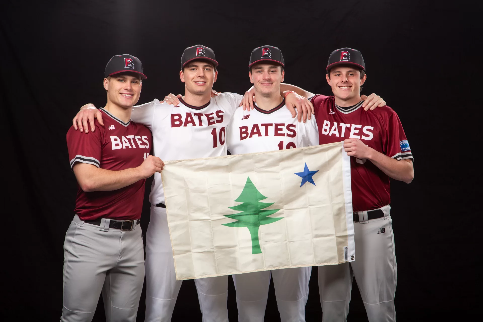 four baseball players holding the old flag of Maine