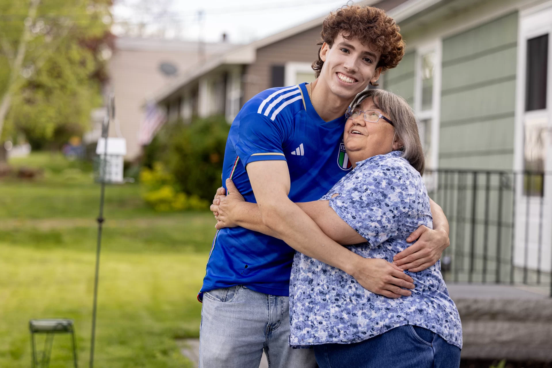 Jose Carmona poses with Carmen Thibodeau outside her home near campus. “Some of my friends know that she’s not my actual grandma,” Carmona says, but others assume it. “They’ll be like, ‘Oh, you’re going to Granny’s house today?” (Phyllis Graber Jensen/Bates College)