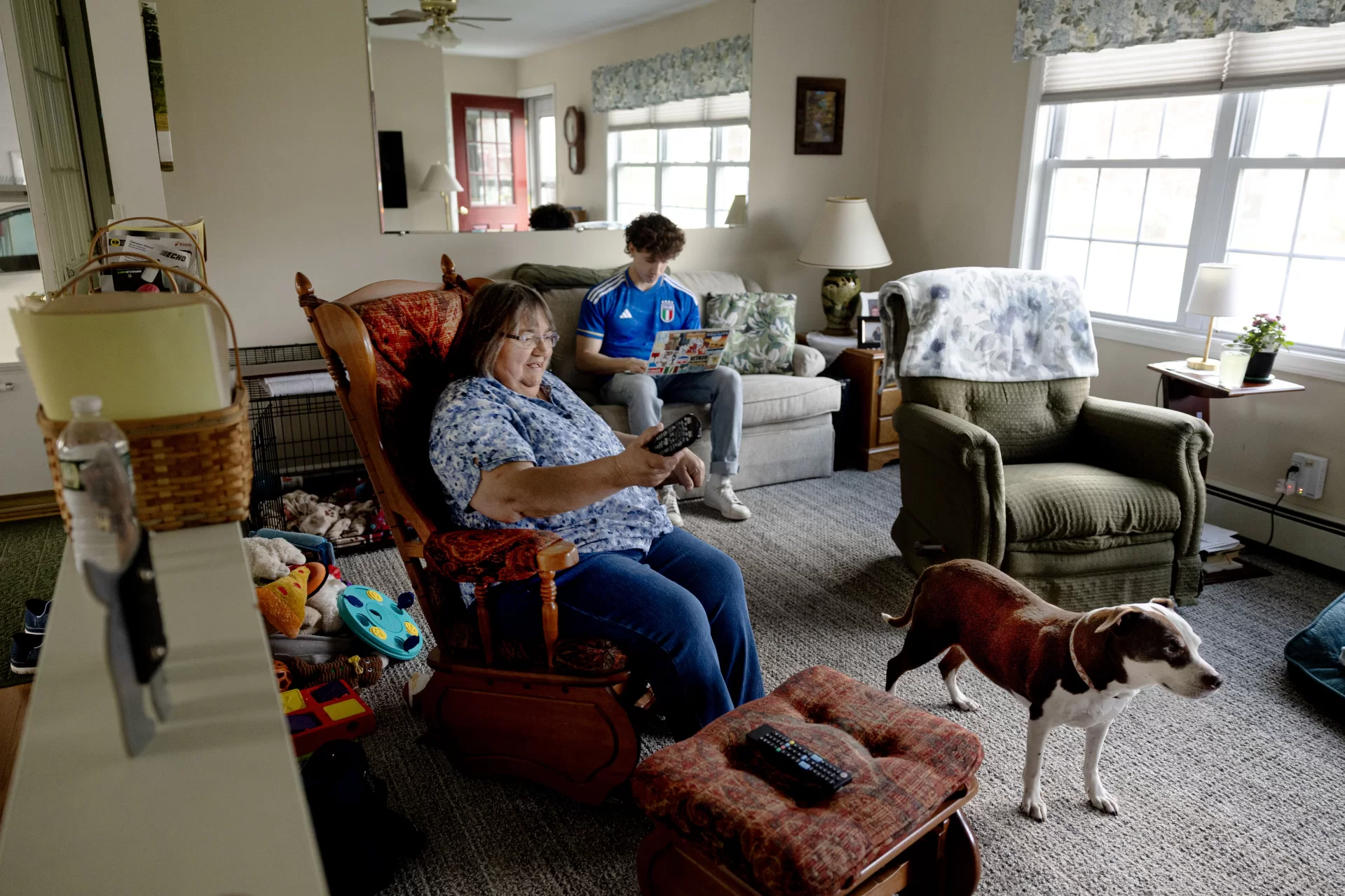 Jose Carmona '25 of Chicago and Carmen Thibodeau hang out in the living room of her home near campus on May 15, 2025, with Thibodeau's dog, Sally. They're not related but she’s been his Lewiston grandmother the whole time he’s been at Bates. (Phyllis Graber Jensen/Bates College)