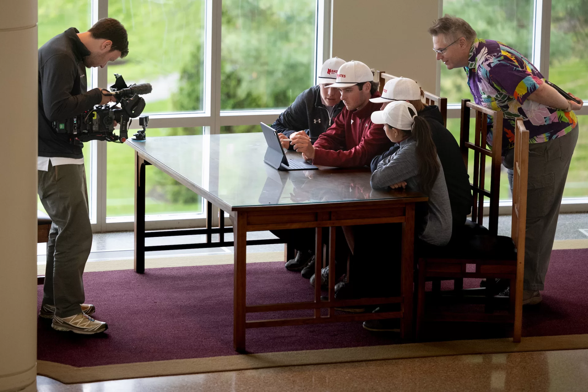 During the afternoon shoot in Pettengill Hall, a camera operator captures the Bates golfers using Adobe Firefly to design their own golf holes. At right is James Lockman, group manager for Adobe. (Phyllis Graber Jensen/Bates College)