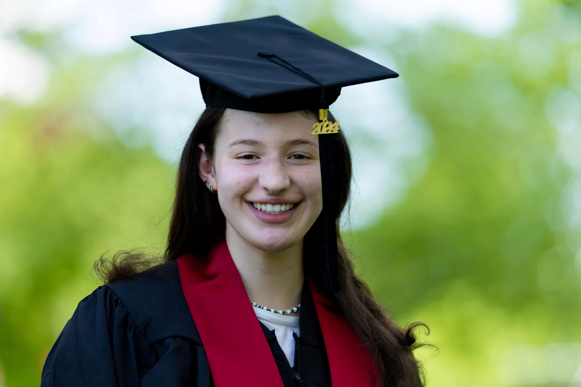 A woman with brown hair poses in a graduation cap and gown