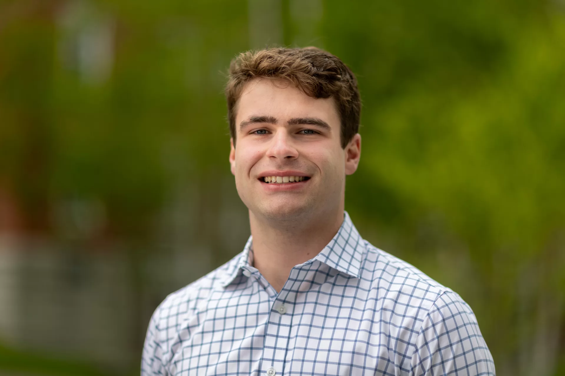 A man smiles for a picture outside.