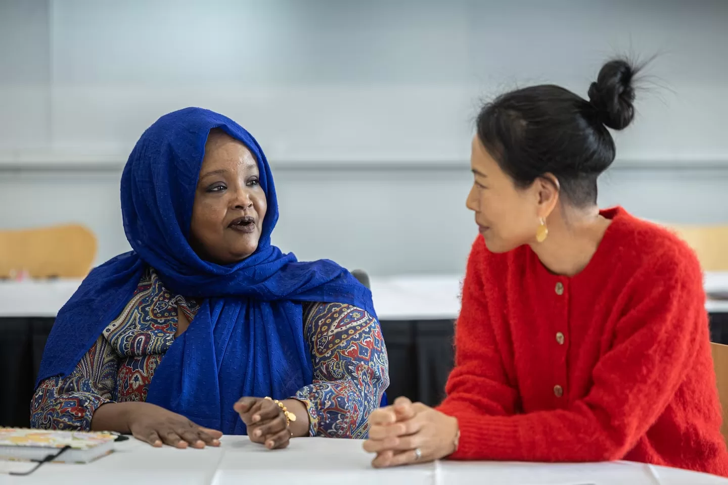 Two women sit at a table and talk.