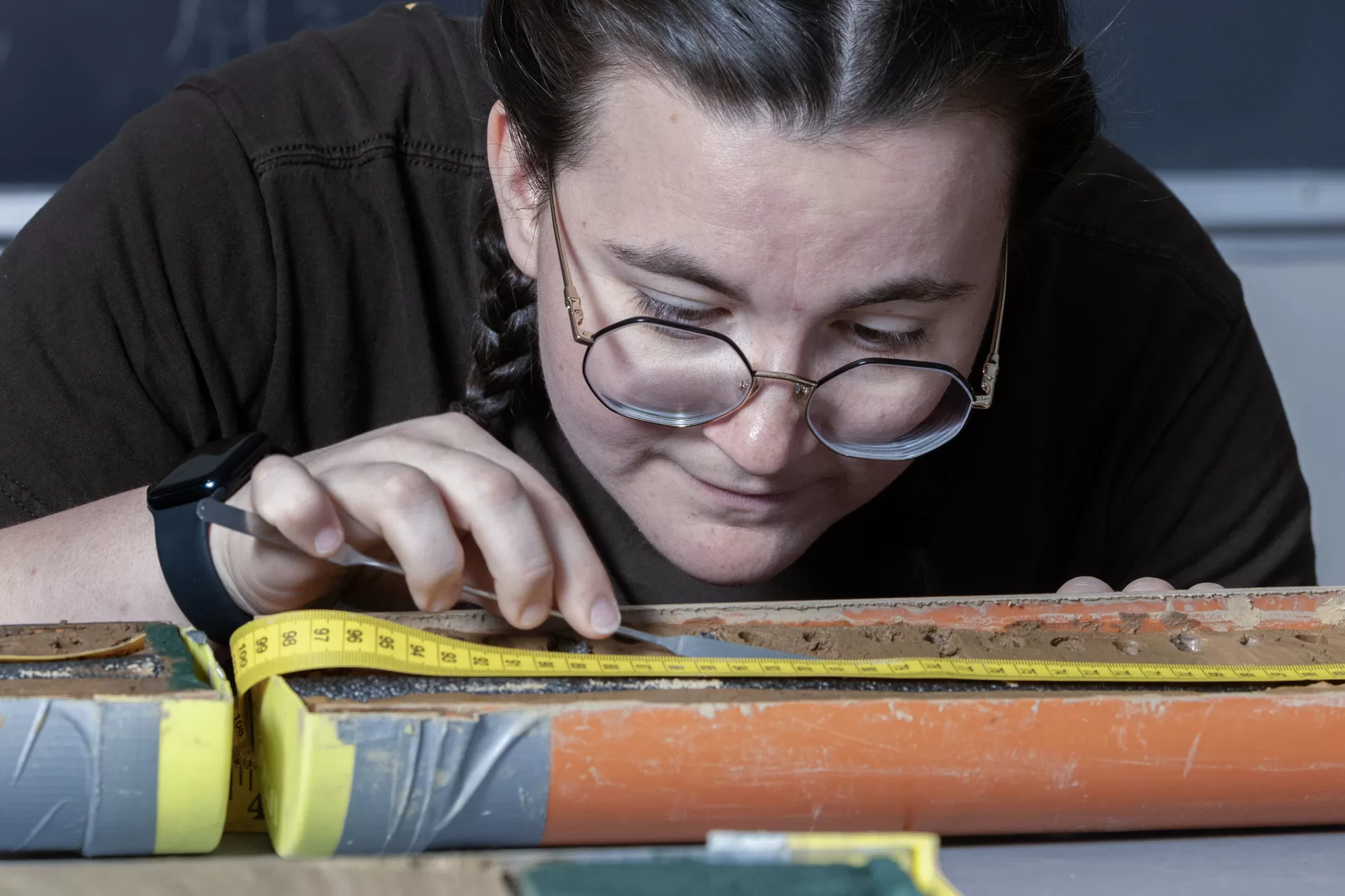 A woman analyzes a sediment sample in a scientific laboratory.