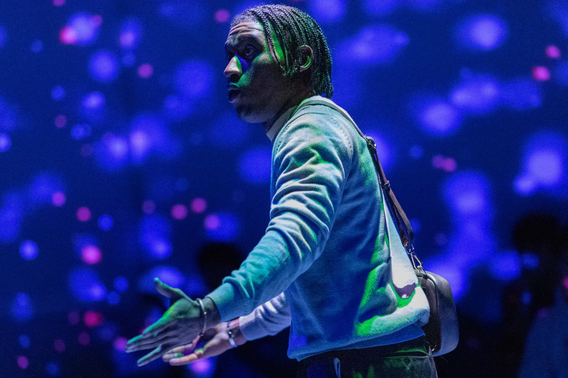 A man moves on a stage in front of colorful lights.