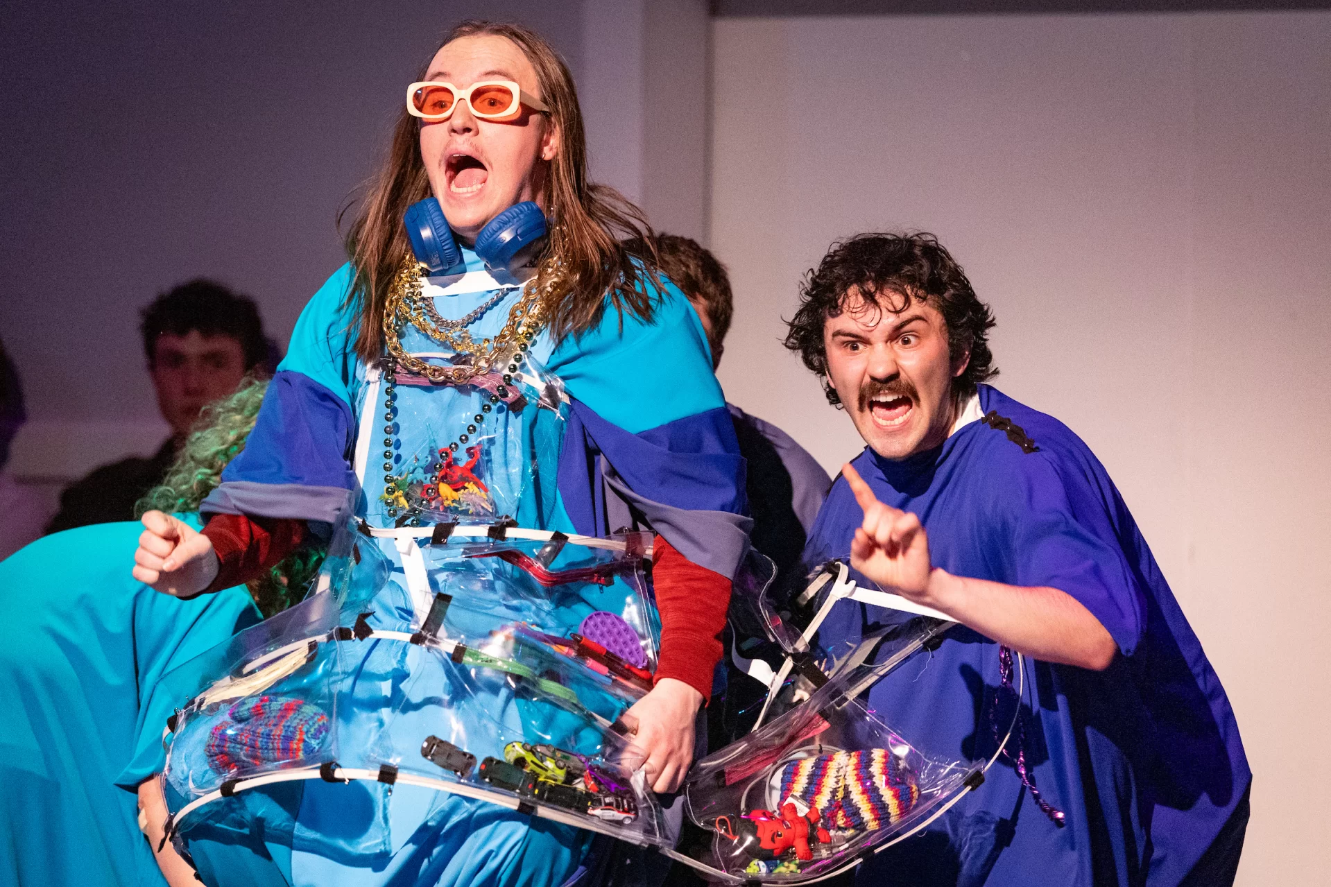 People exclaim in colorful outfits onstage.