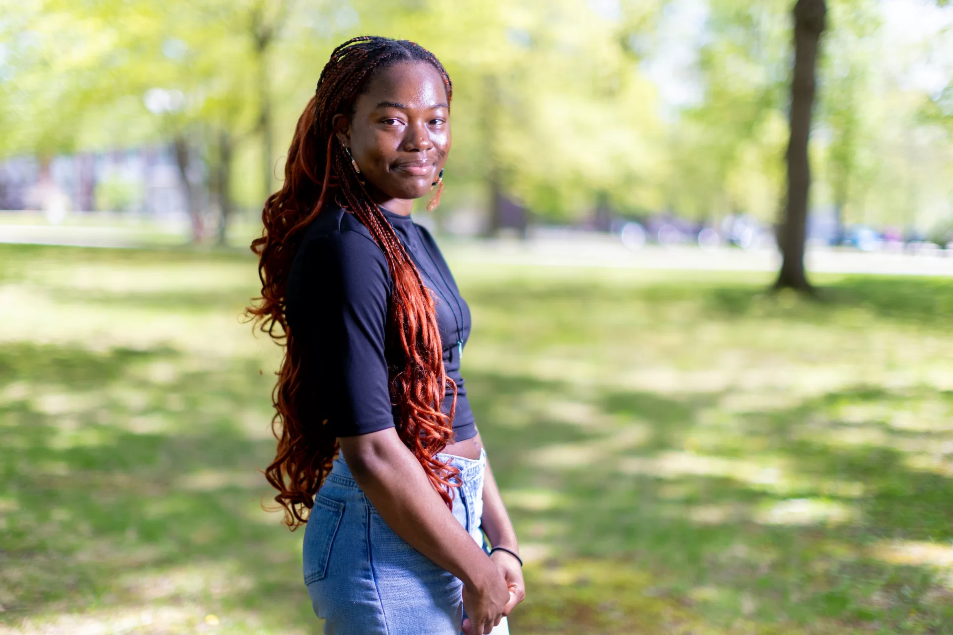 A woman smiling and standing outside on grass.