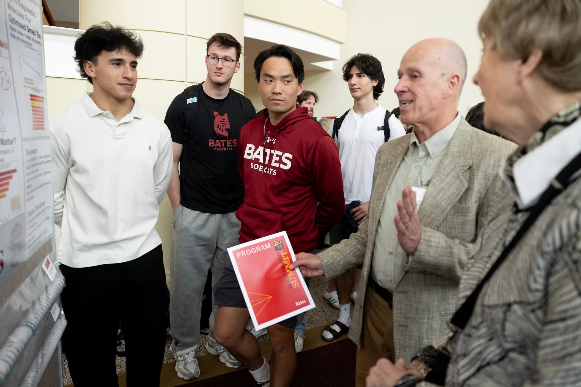 A group of people standing in front of a poster.