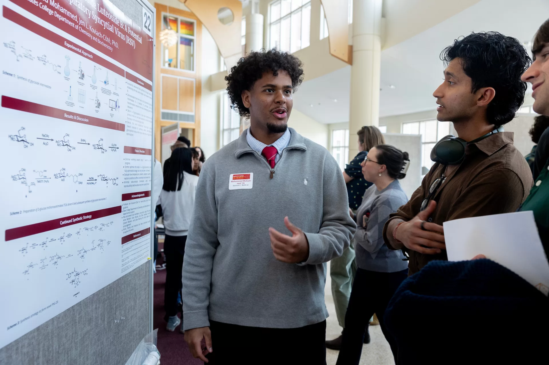 A man standing next to a poster speaking to a group of people.