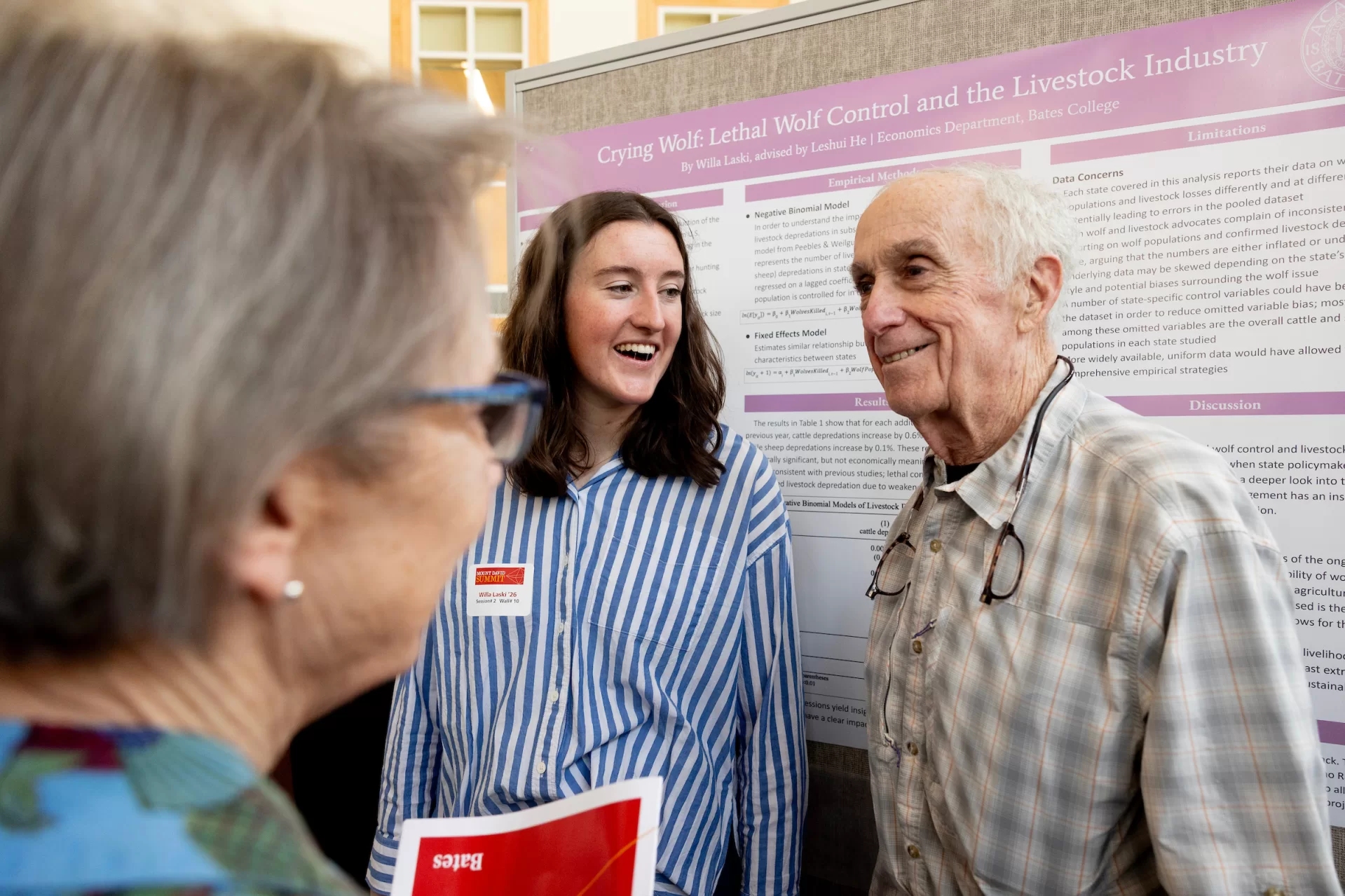 A man and woman standing in front of a poster smiling.