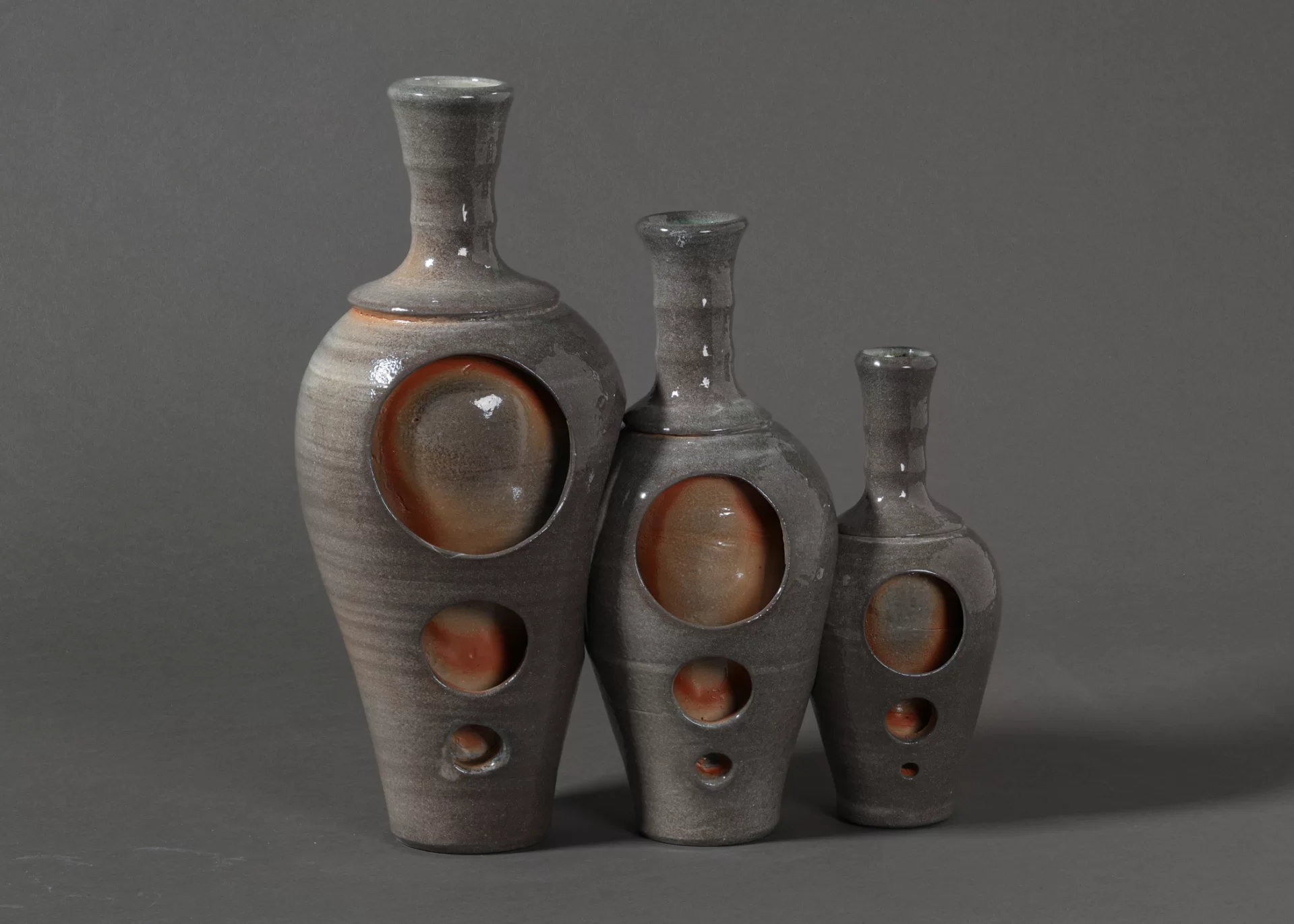 Three gray ceramic vases, each smaller than the previous but otherwise identical.