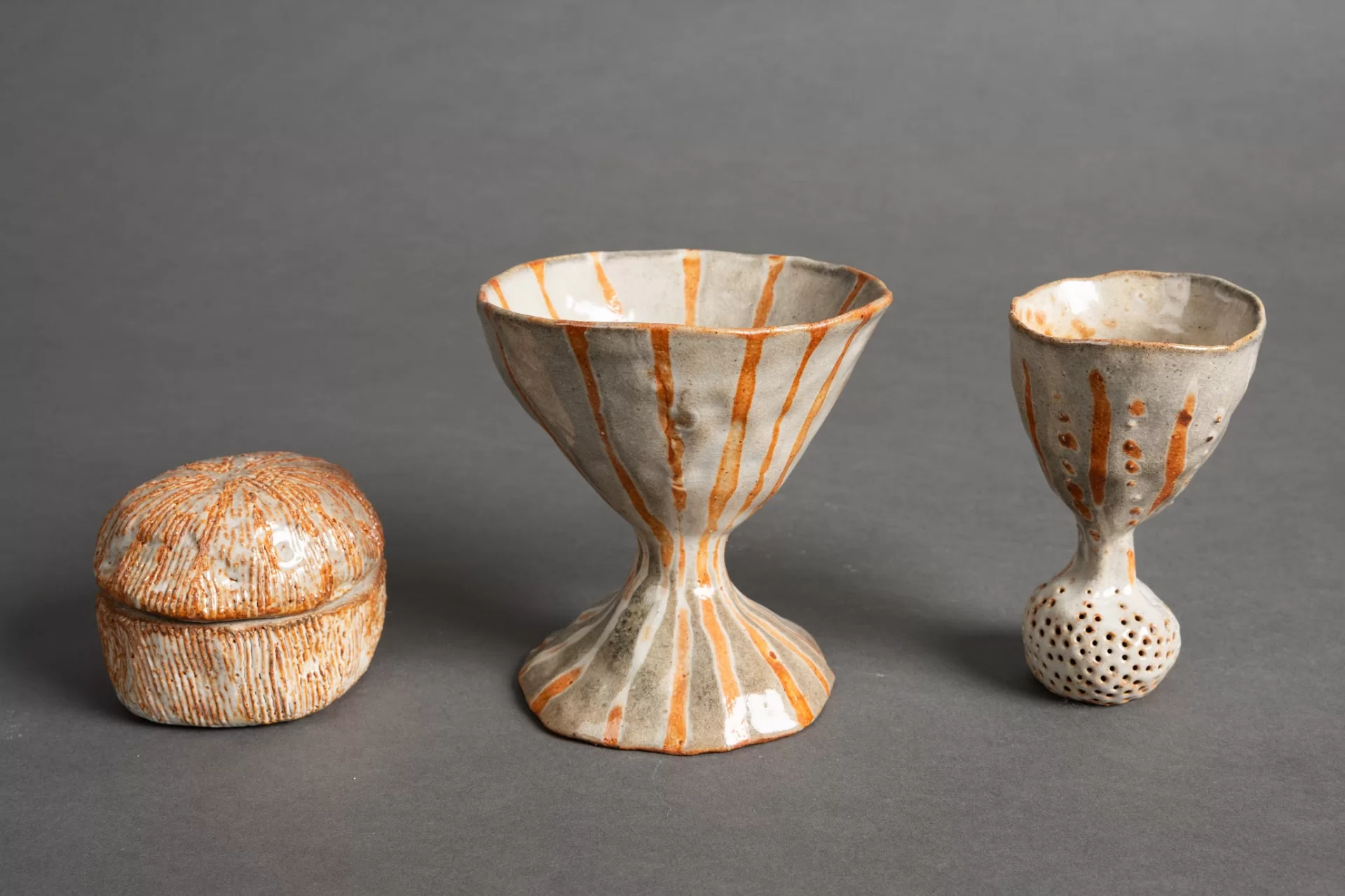 Three orange and white ceramic vessels.