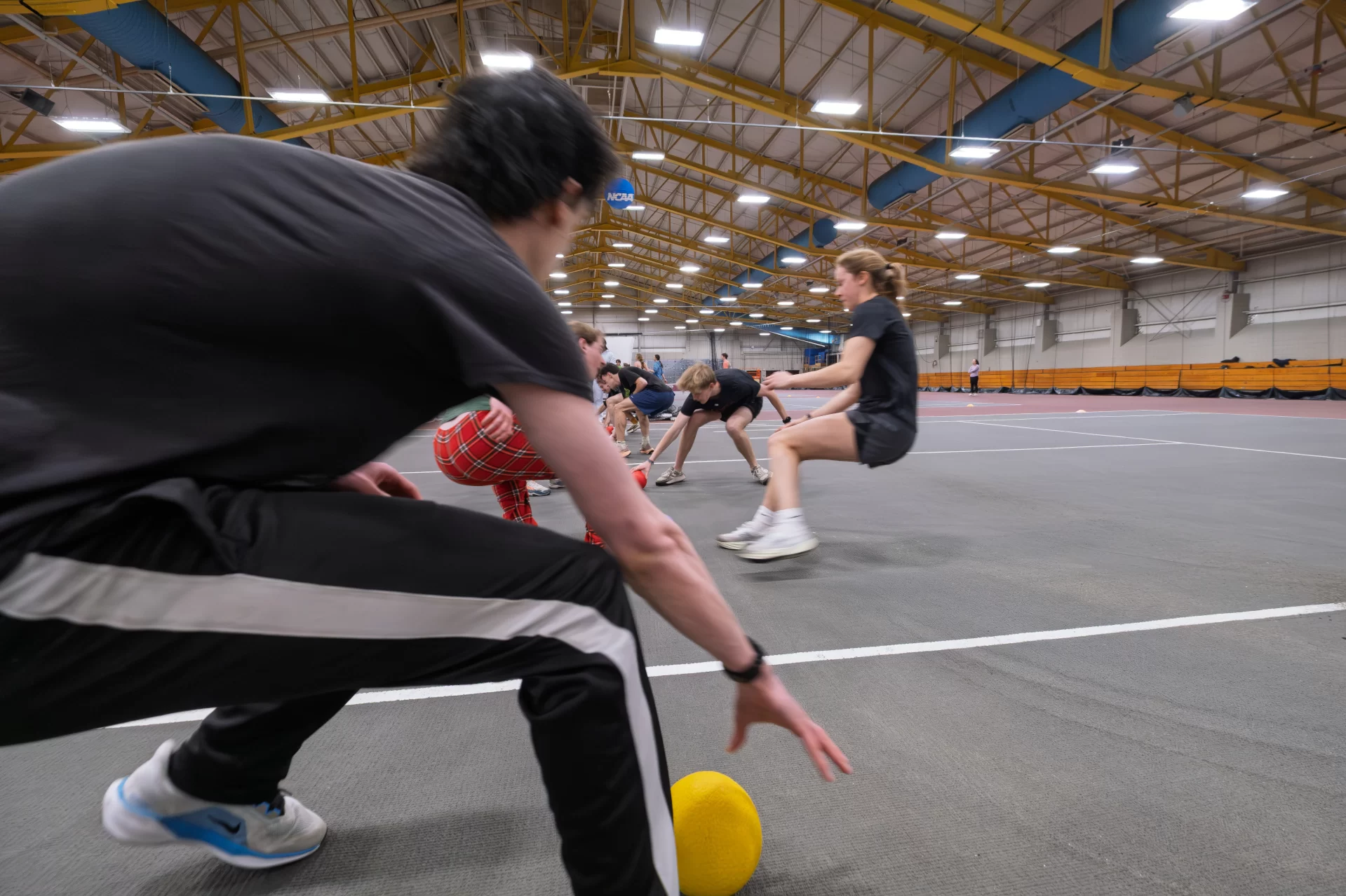 Students grab balls off a court at the beginning of a dodgeball game.