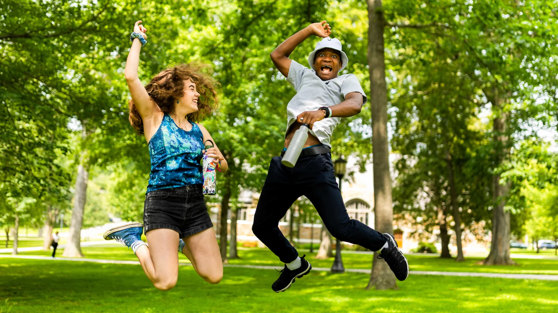 A woman and a man jumping in the air outside