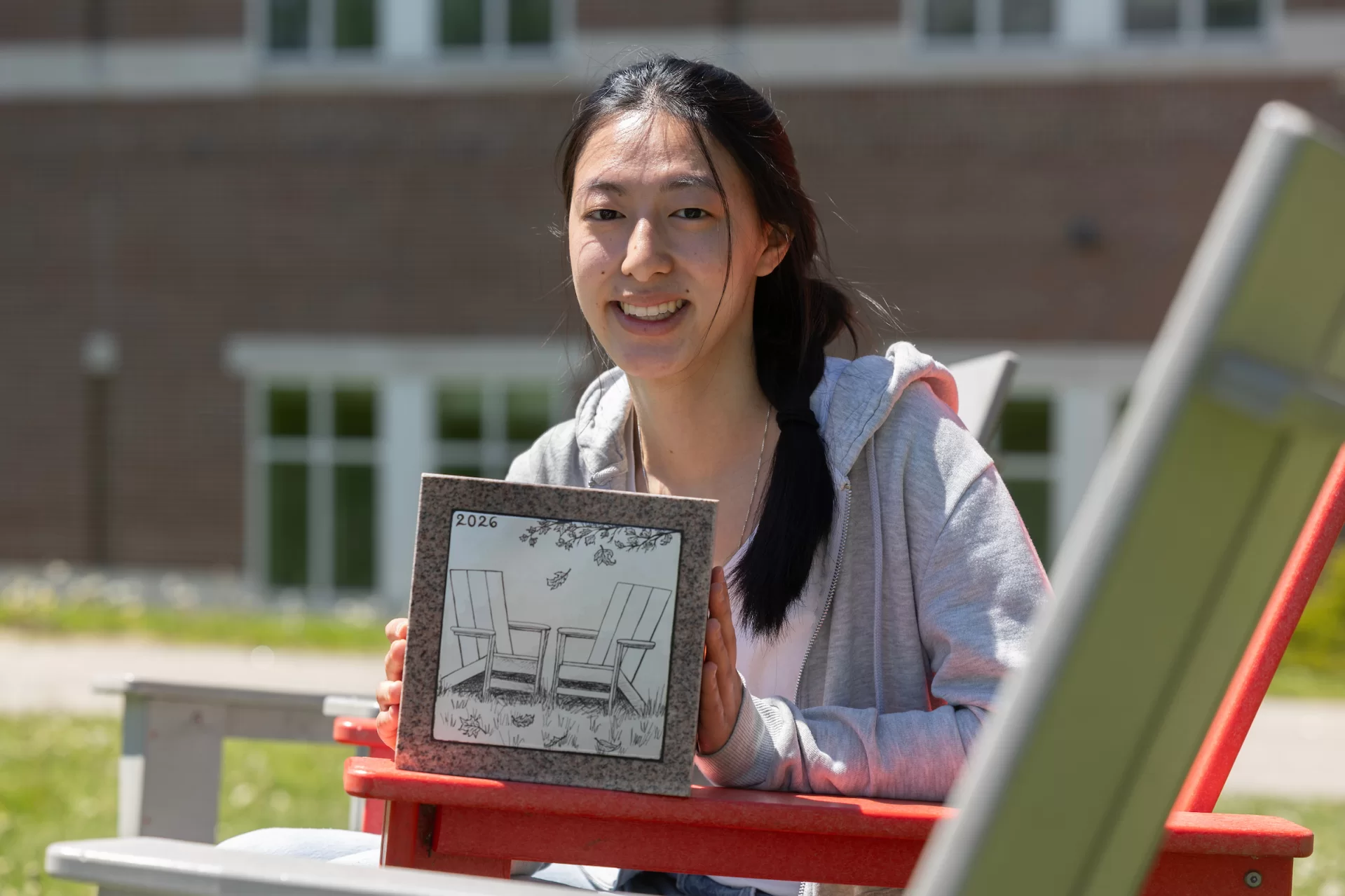A woman holds up a decorative stone outside.