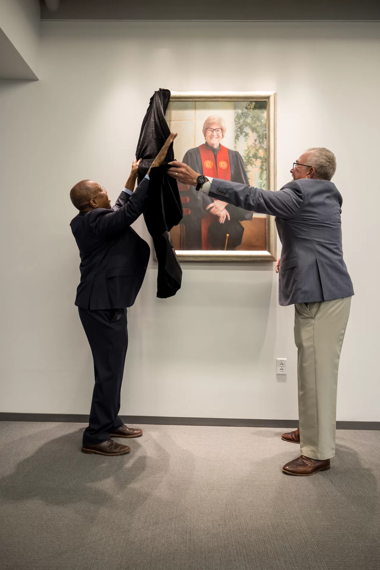 Two men lifting a curtain off of a painting